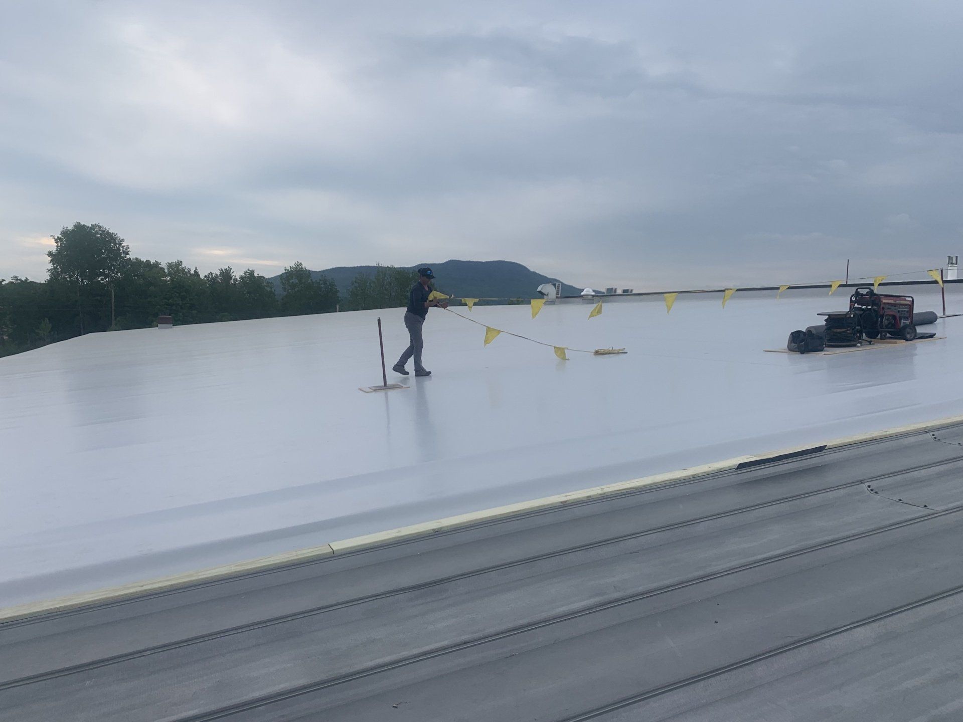 Early morning Metal Roof Retrofit with a worker amidst a scenic mountain backdrop.