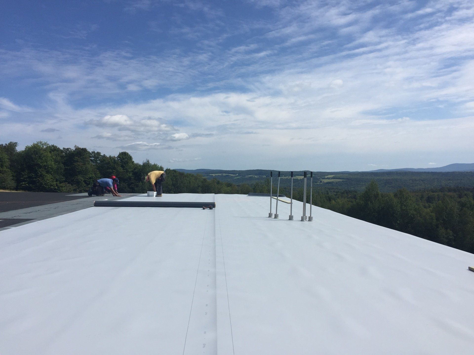 A man is standing on top of a white roof.