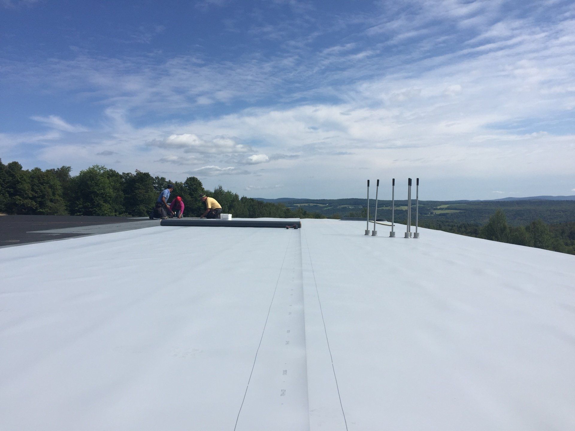 A group of people are standing on top of a white roof.