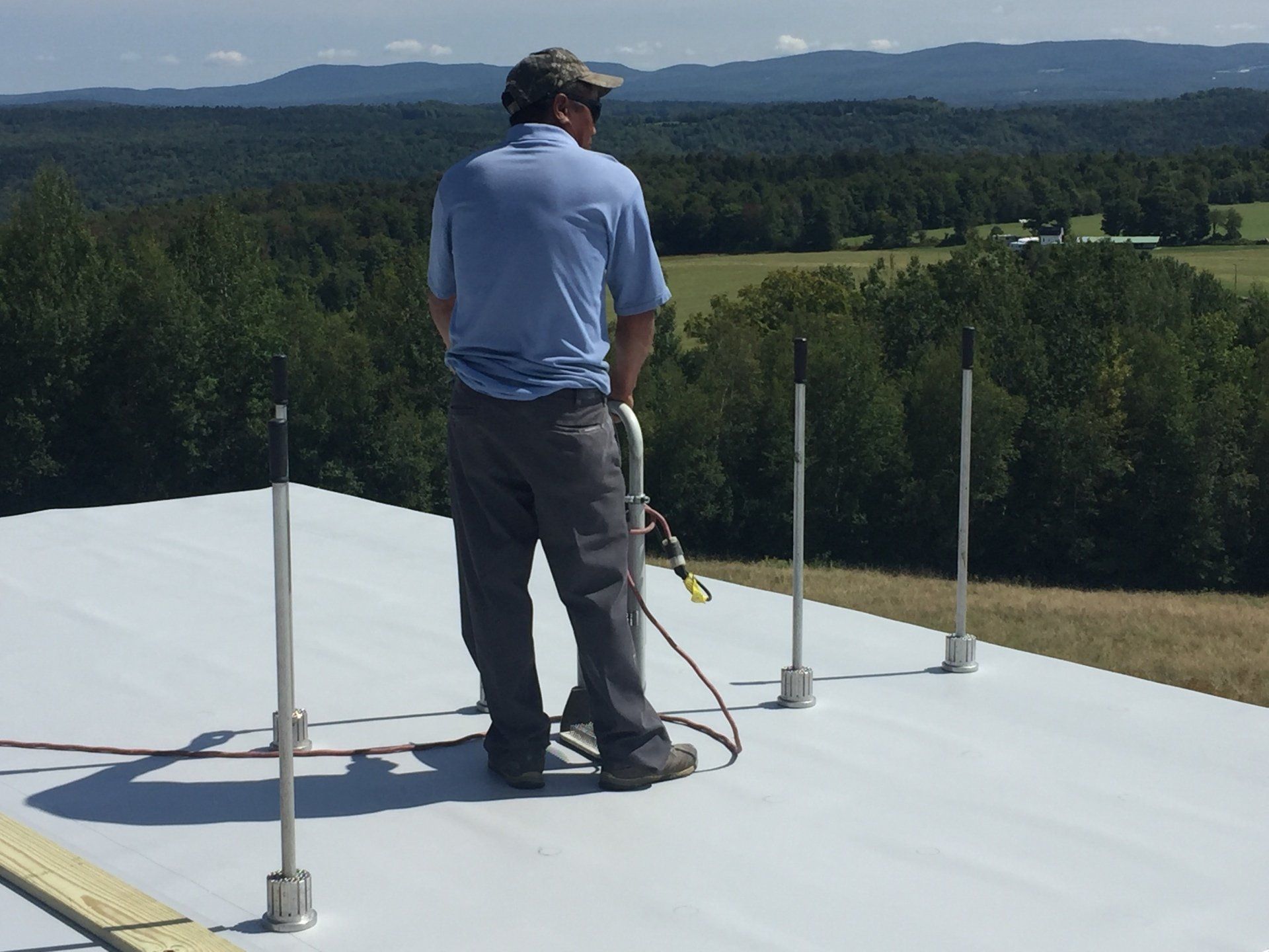 A man in a blue shirt is standing on a white roof
