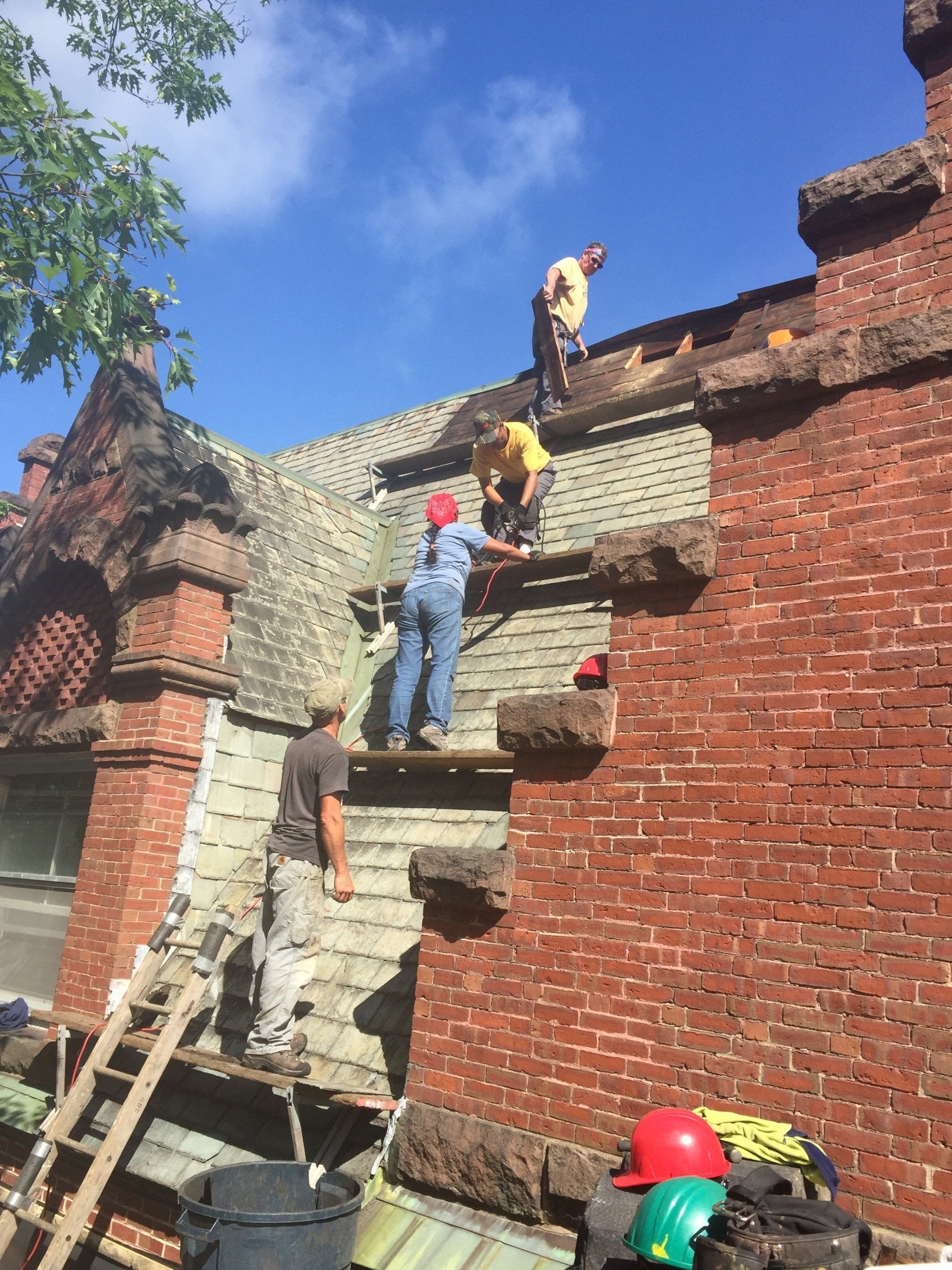 A group of men are working on the roof of a brick building.