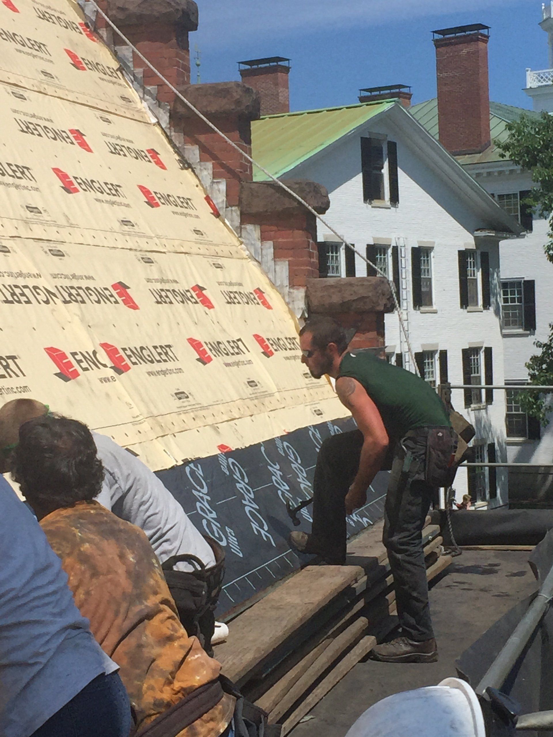 A man in a green shirt is working on a roof