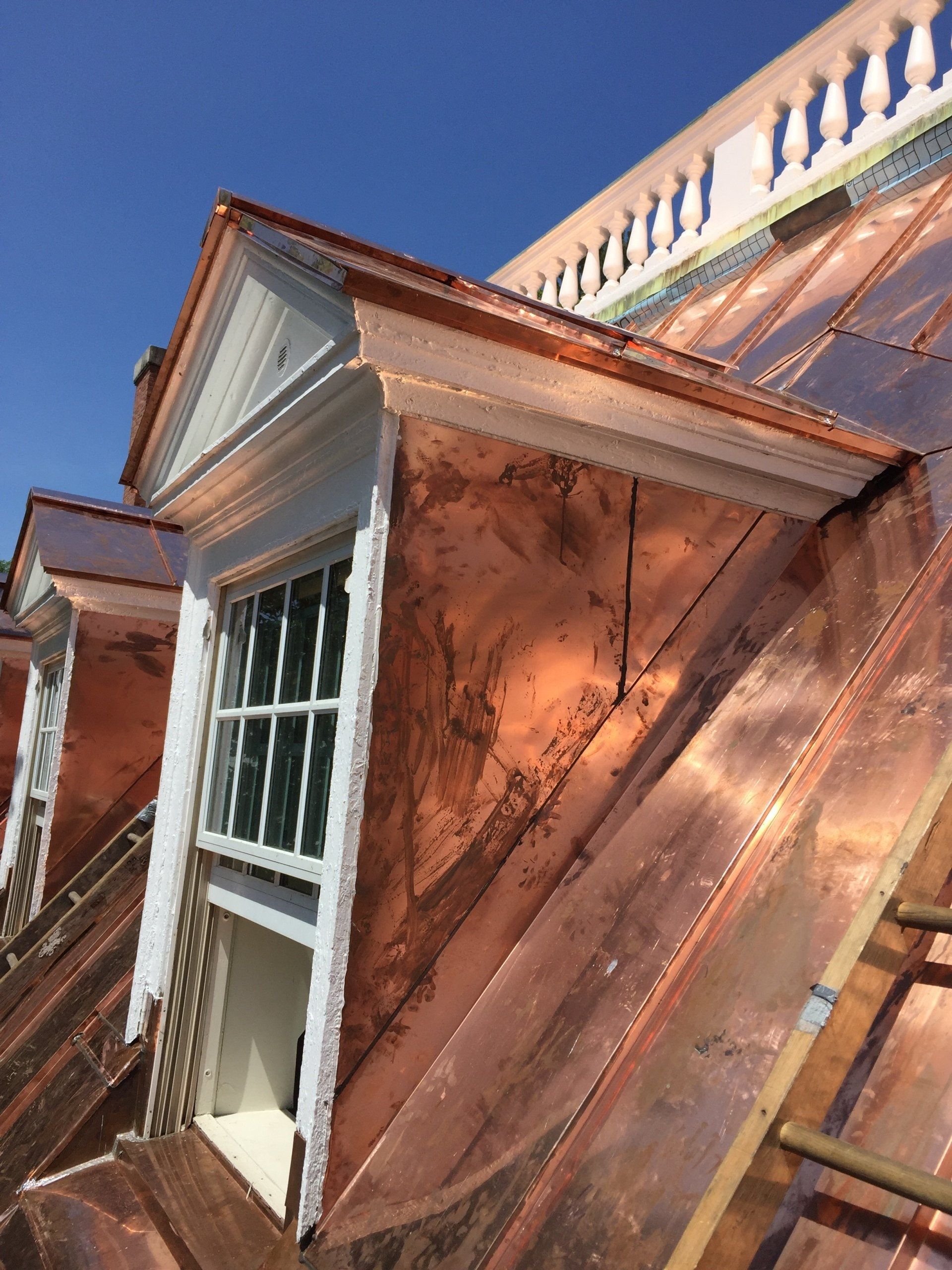 A copper roof with a window on the side of a building.