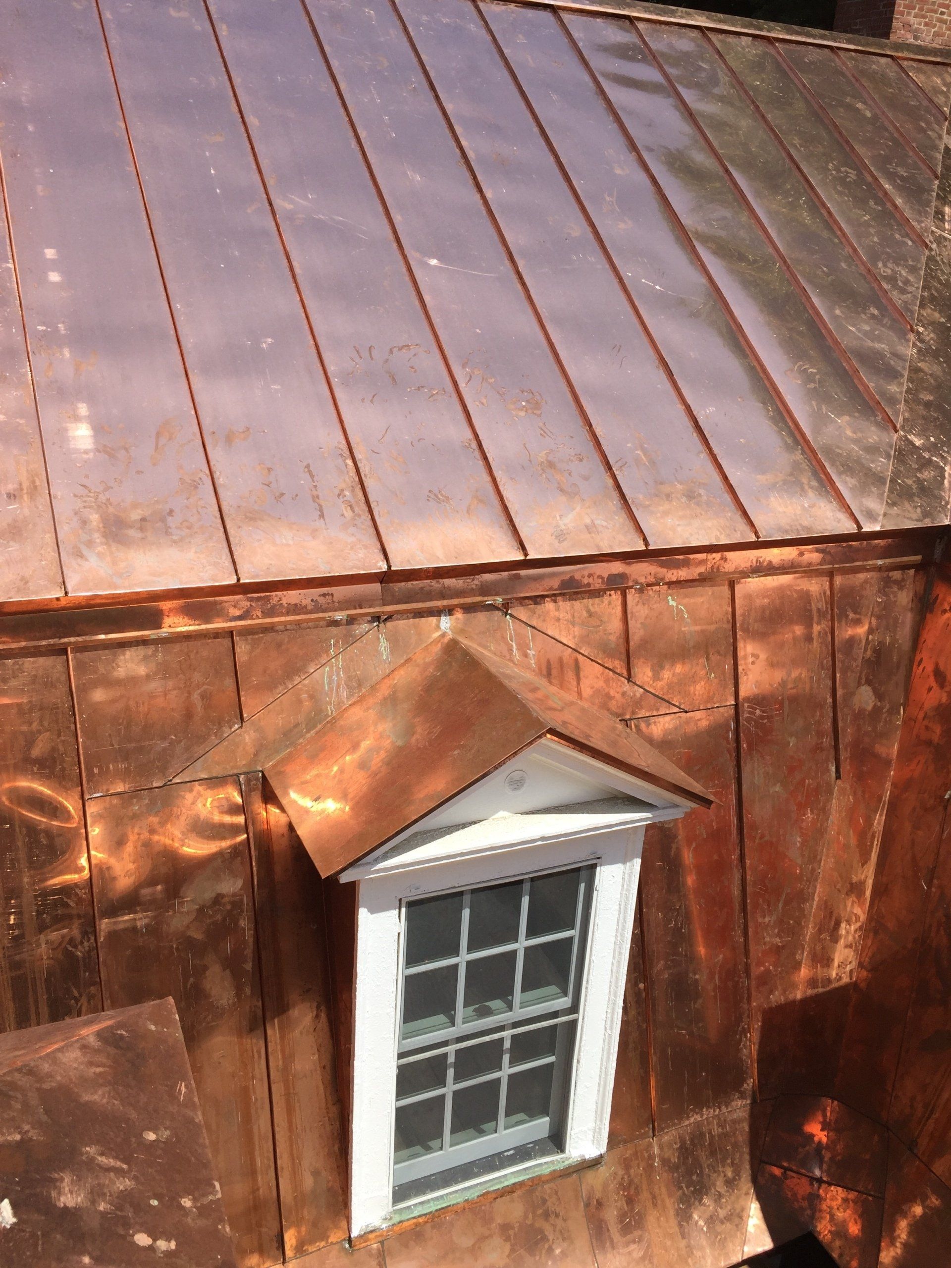 A window on the side of a building with a copper roof