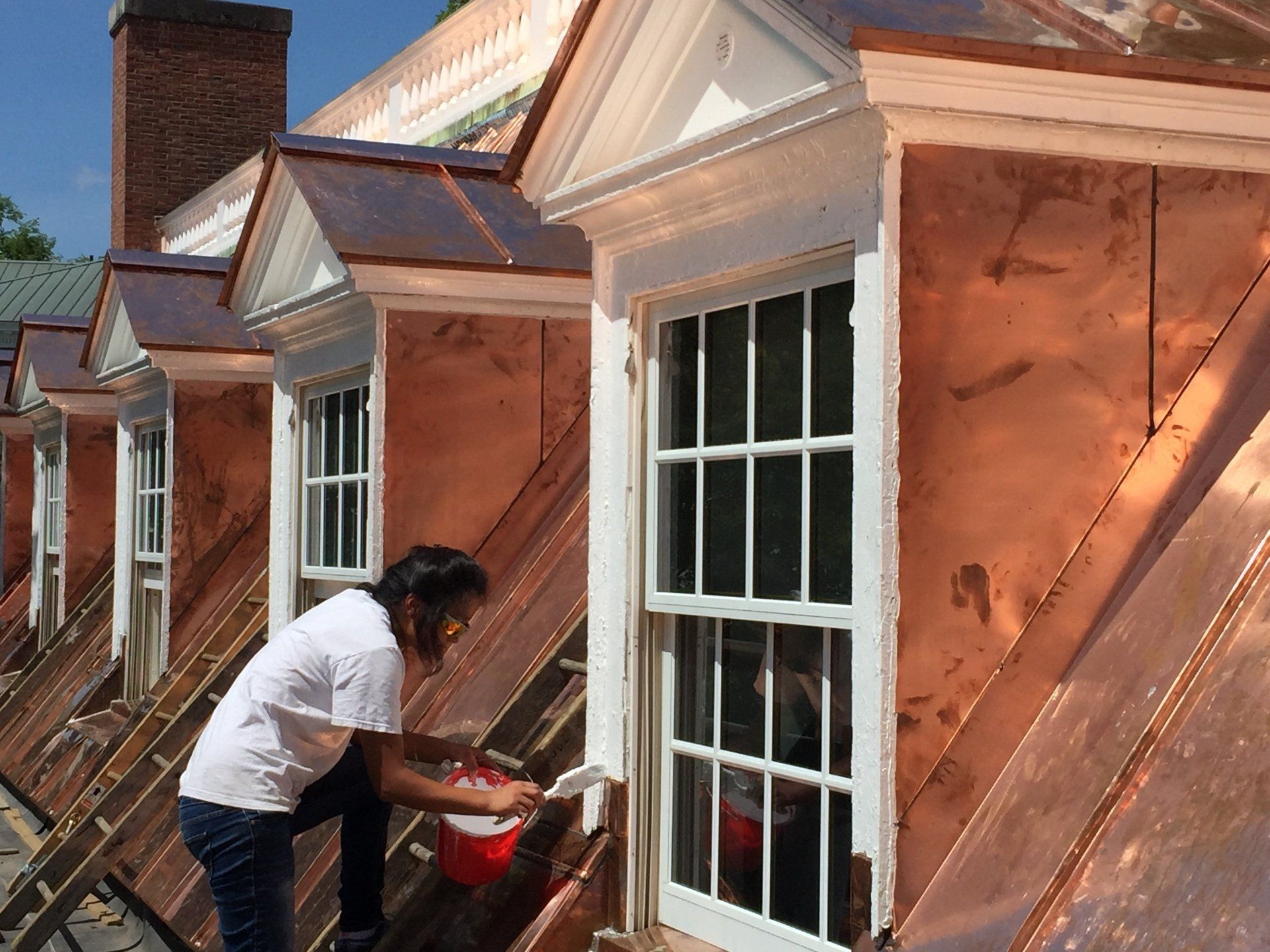 A man is working on a copper roof of a building