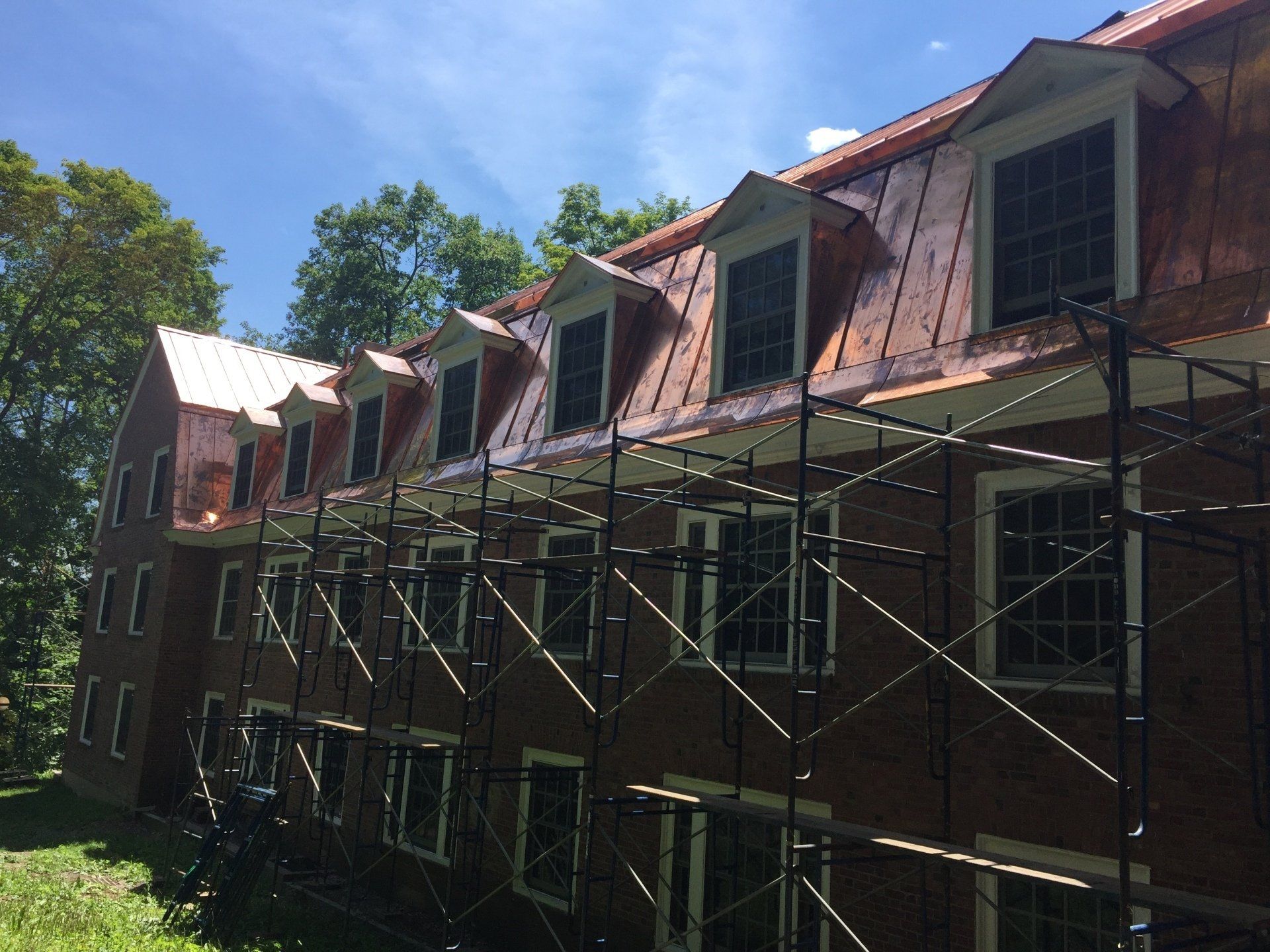 A brick building with scaffolding around it and a copper roof