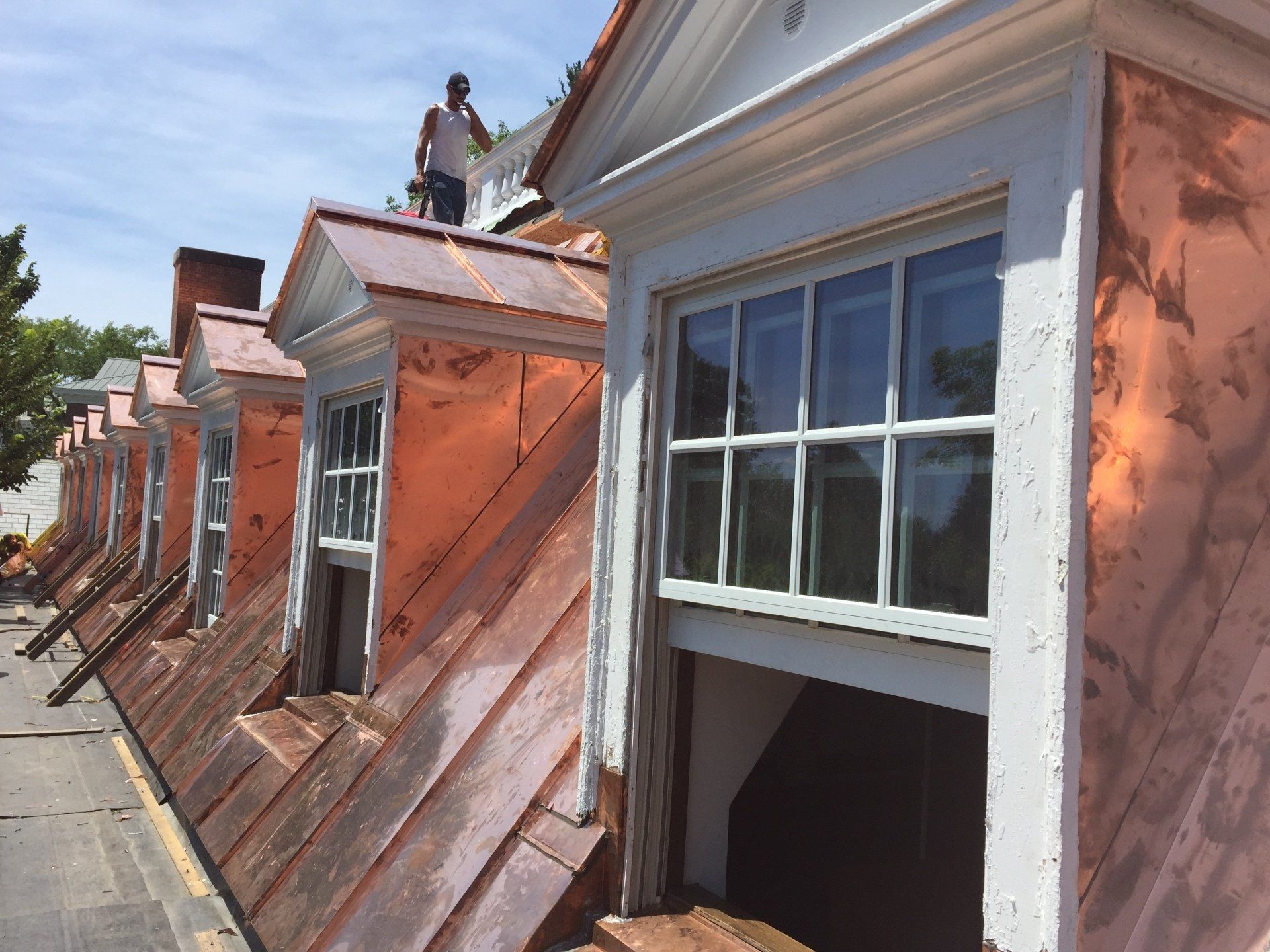 A man is standing on the roof of a building with copper roofing