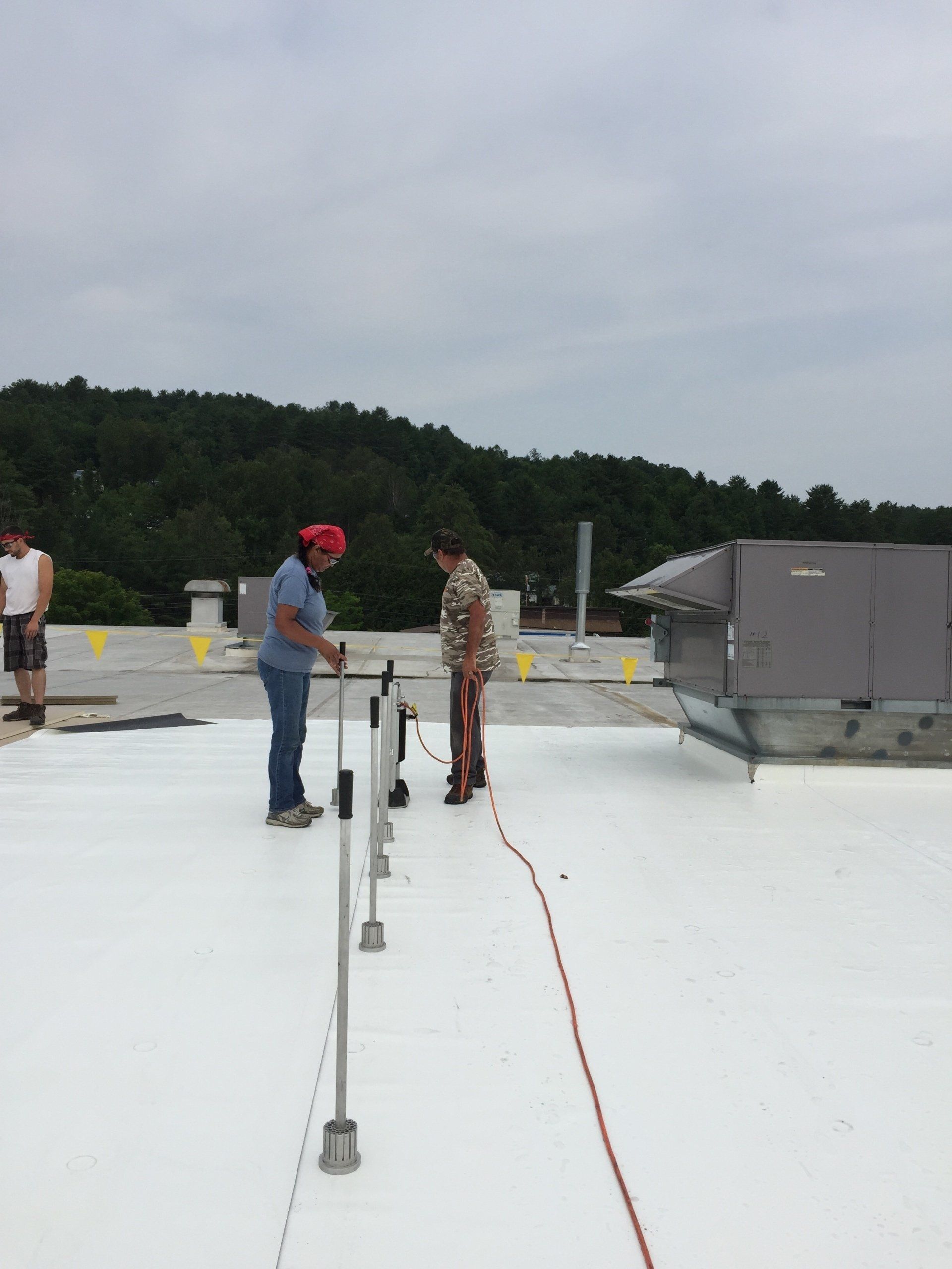 A group of people are working on a white roof.