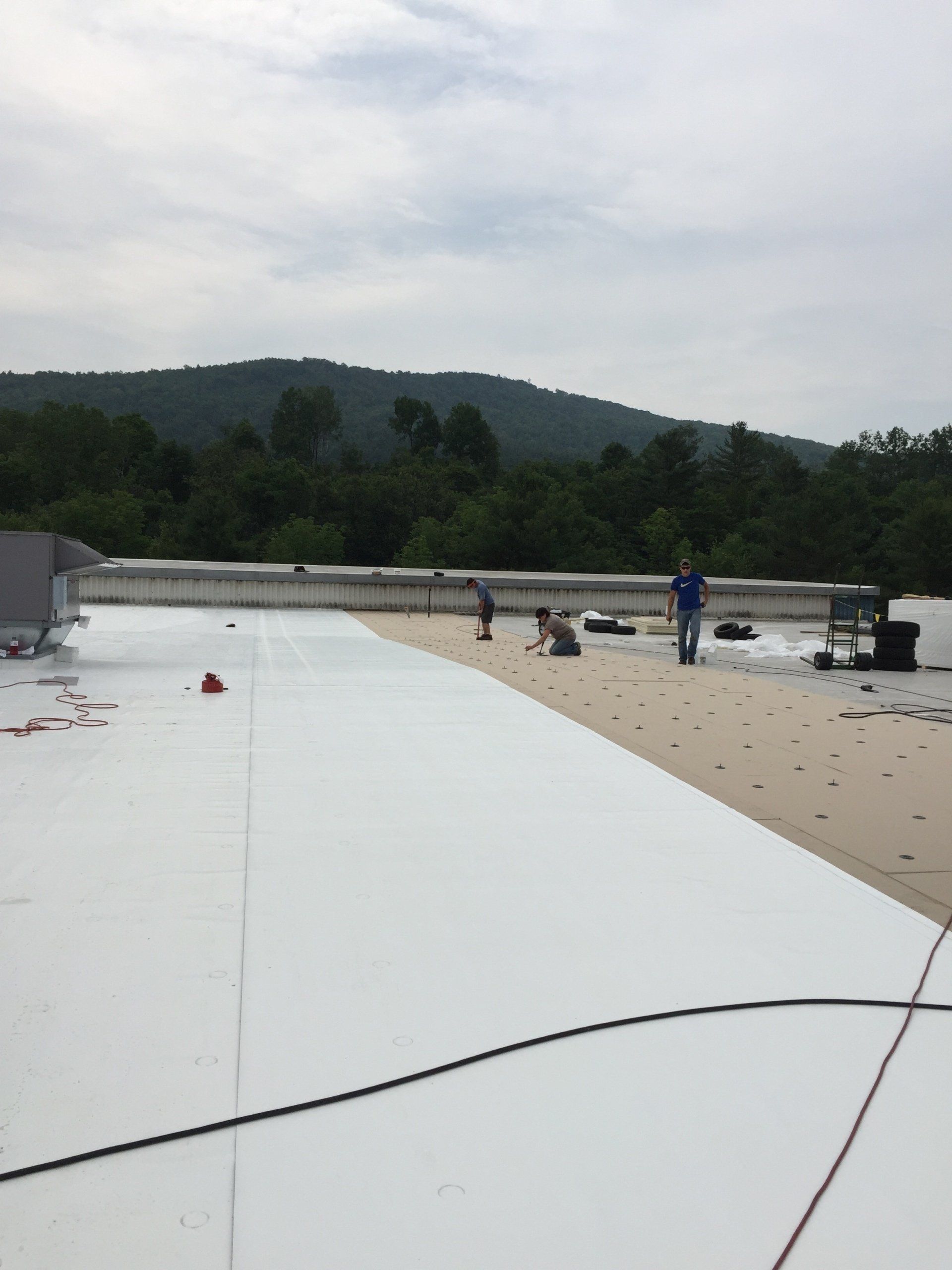 A man standing on top of a white roof with mountains in the background