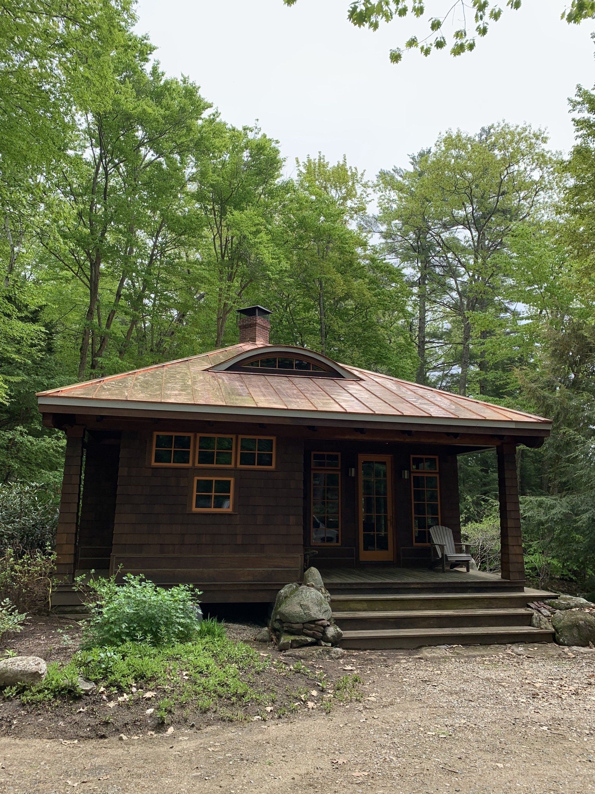 A small wooden house in the middle of a forest surrounded by trees.