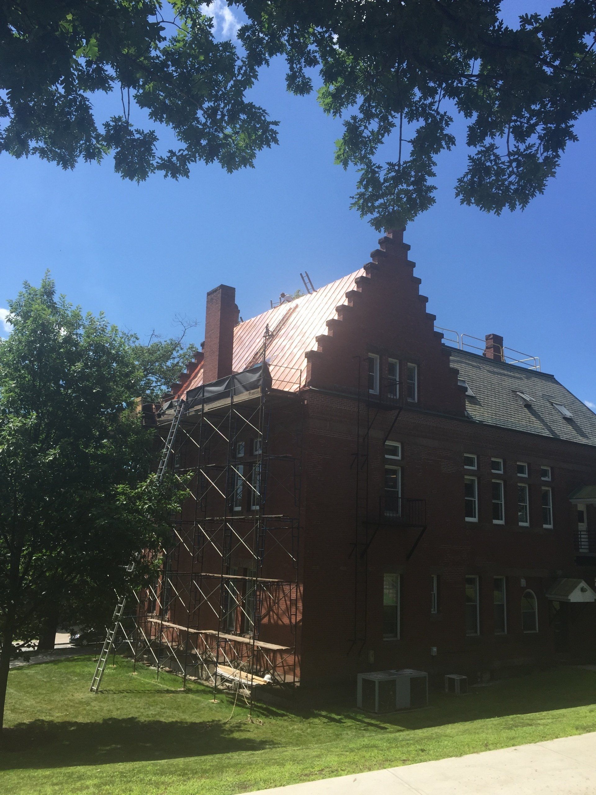A large brick building with a copper roof is under construction