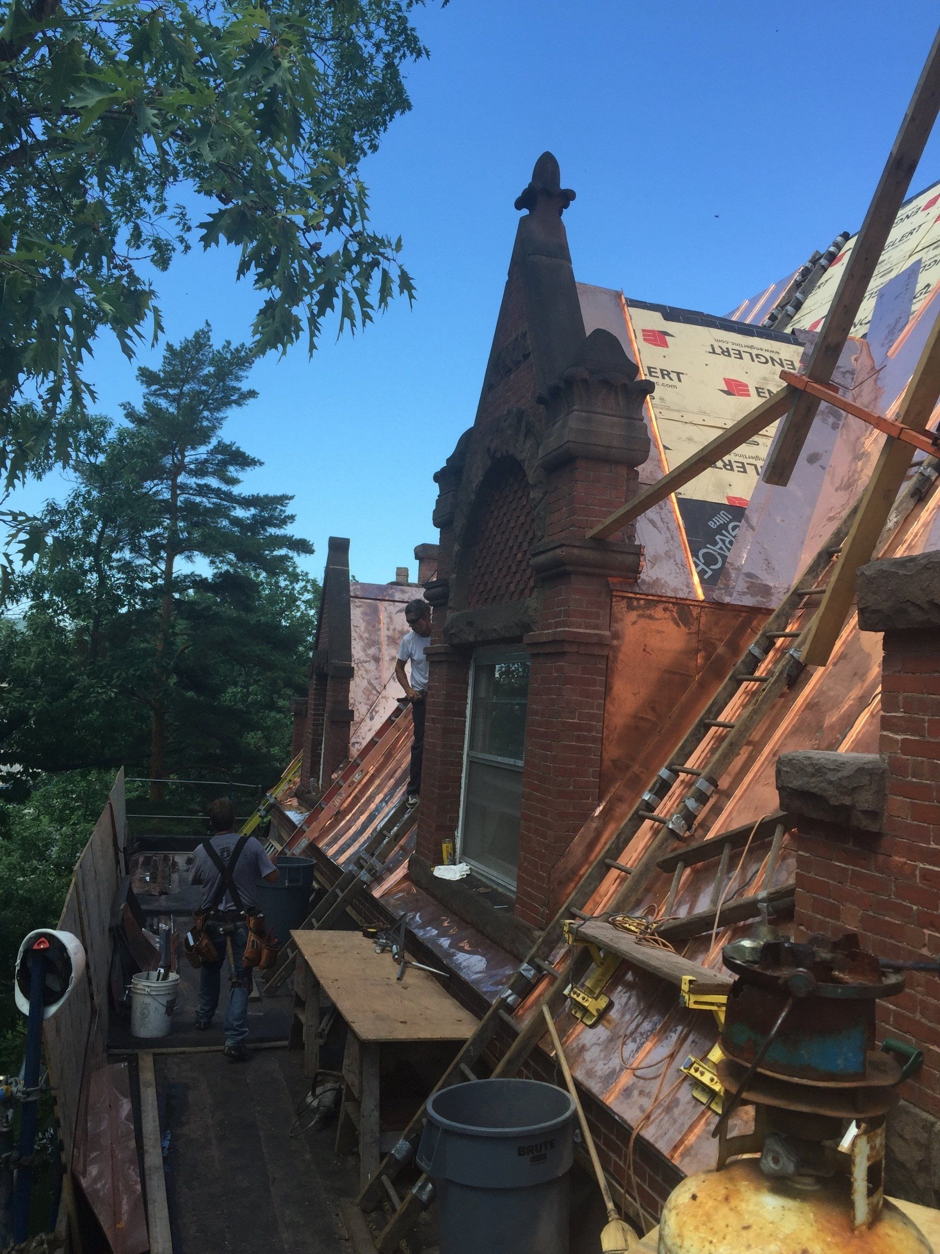 A copper roof is being installed on a brick building.