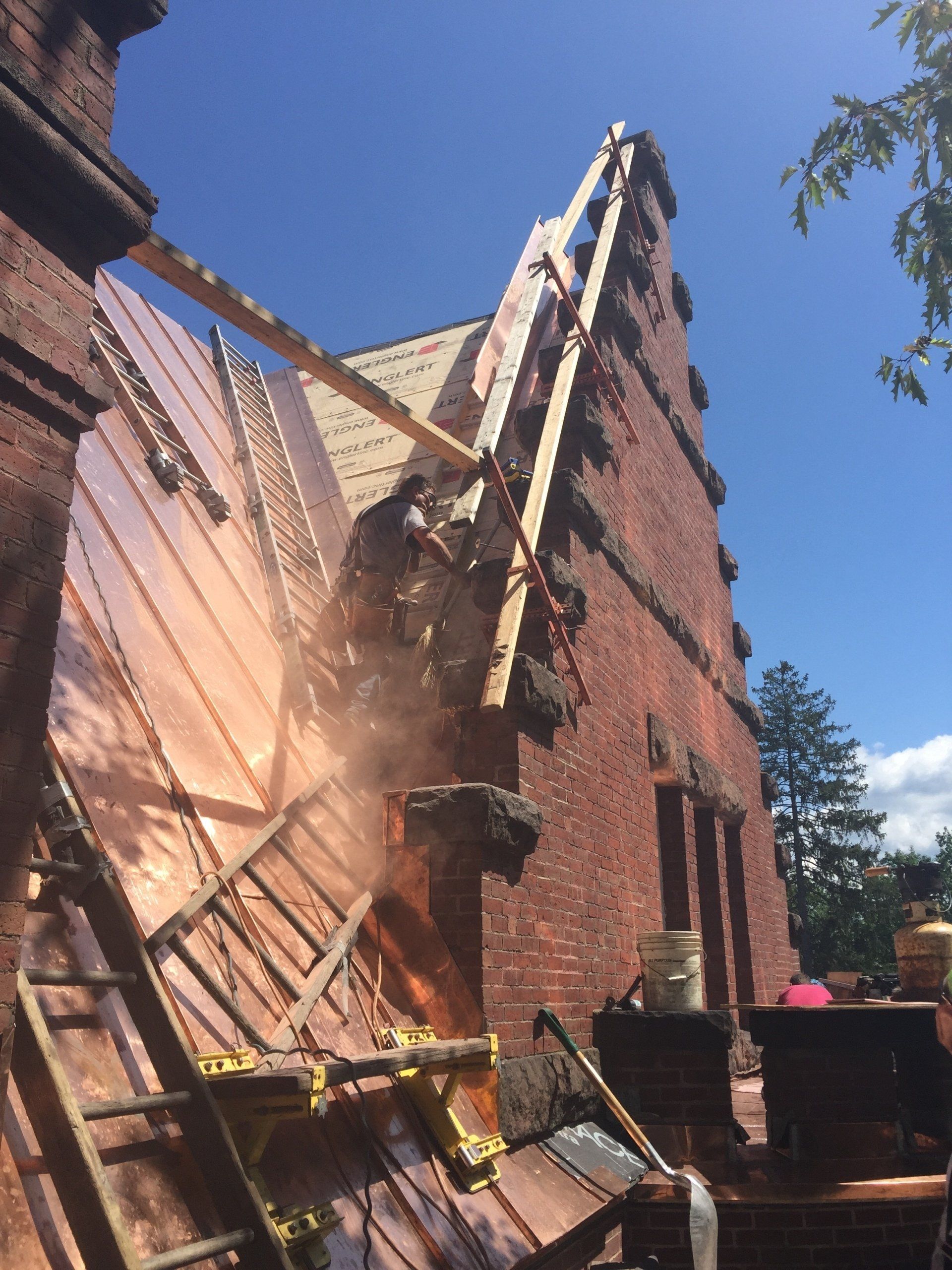 A copper roof is being removed from a brick building
