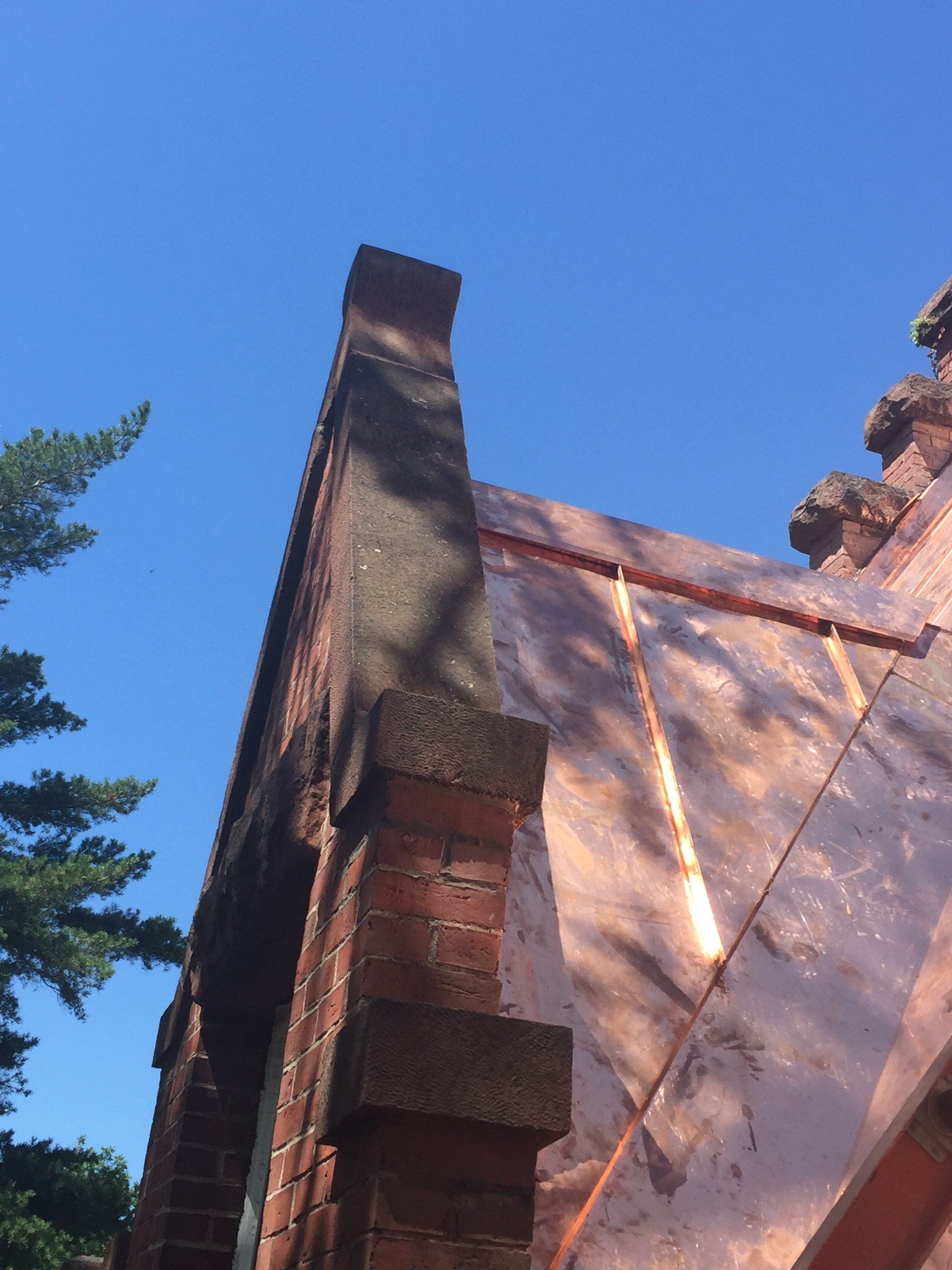A brick building with a copper roof and a chimney.