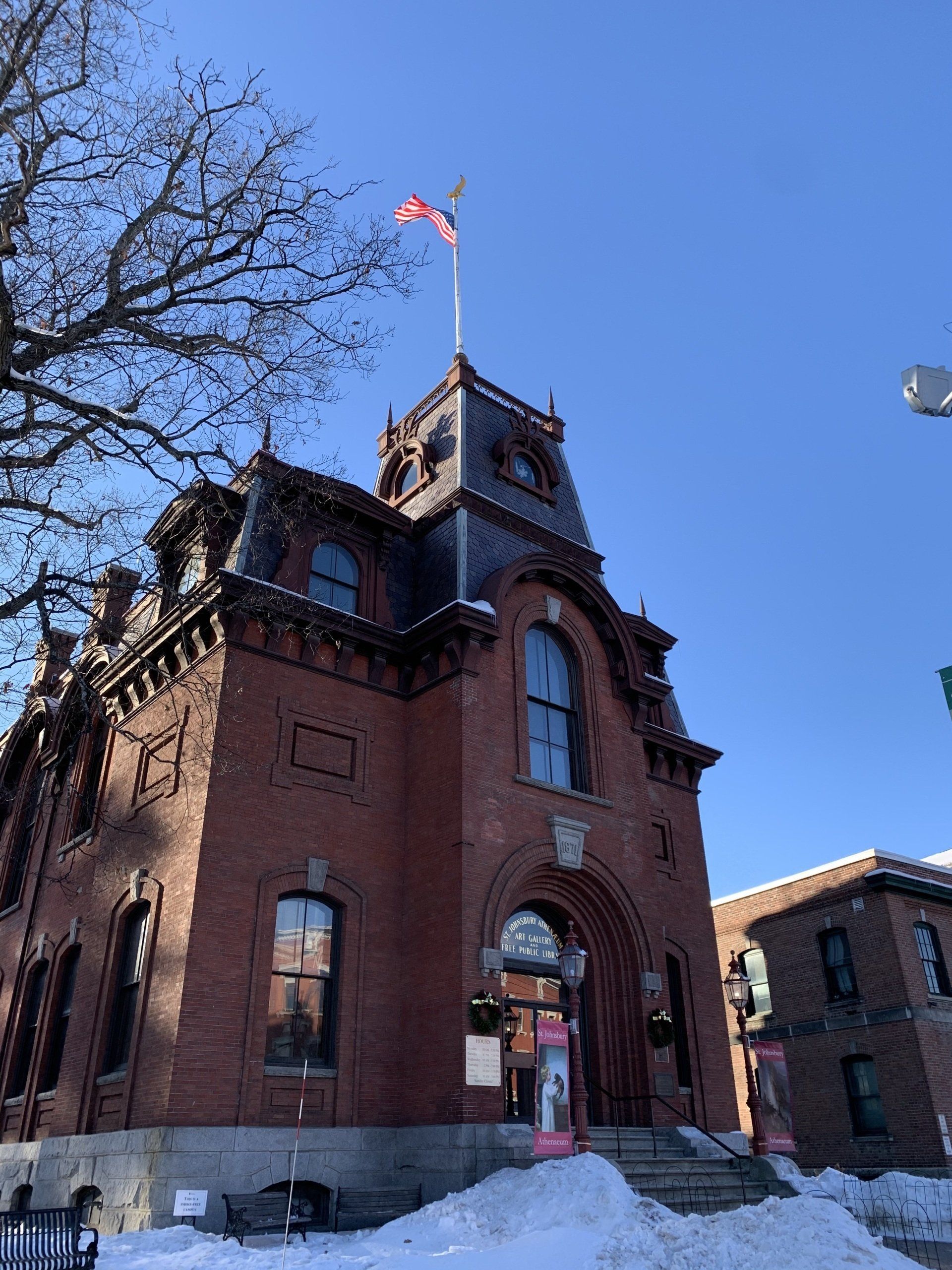 single-ply projects - ictorian red brick building with arched entrance and clock tower on a snowy day.