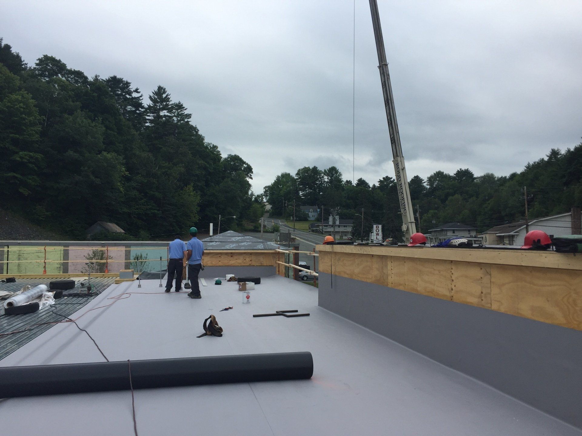 Two men are standing on a roof with a crane in the background