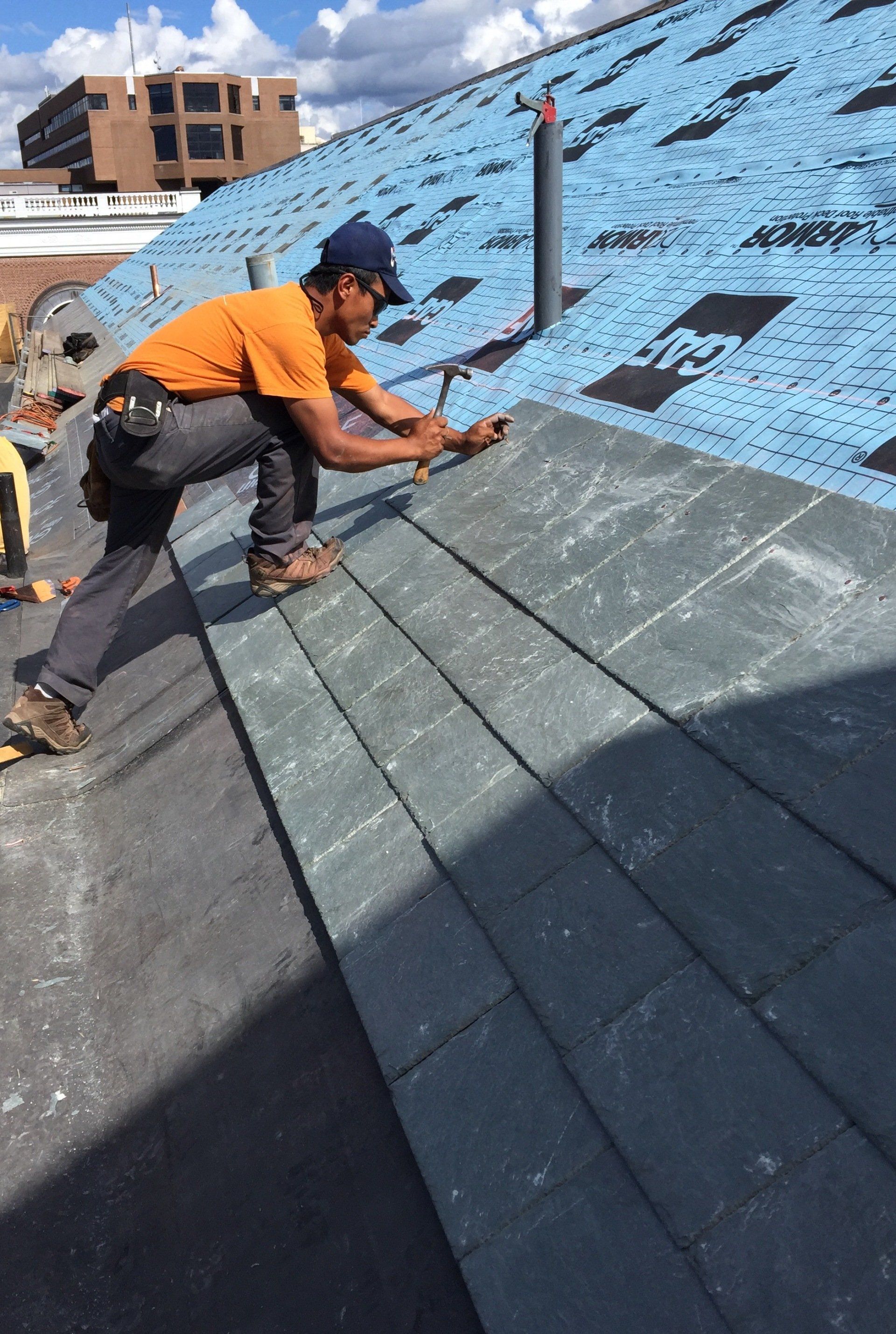 A Vermont slate roofs expert from Rodd Roofing installs freshly prepared slate shingles on a Vermont commercial roof