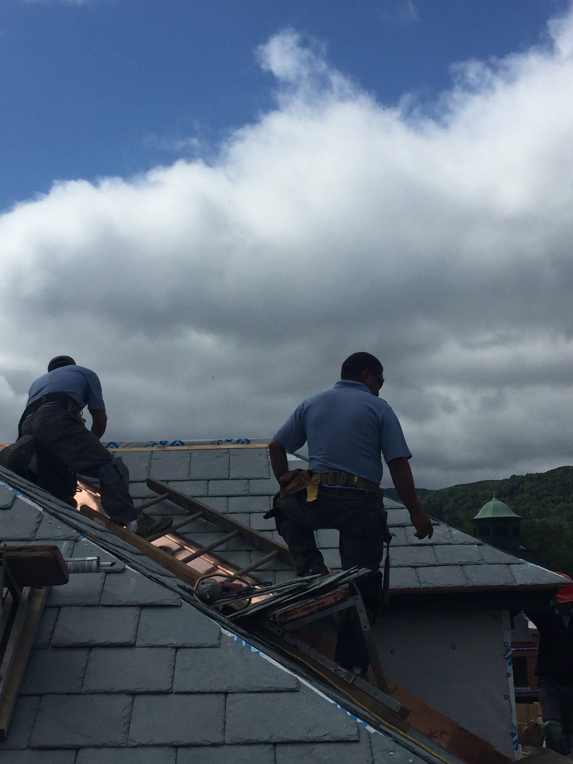 Two men are working on the roof of a building.