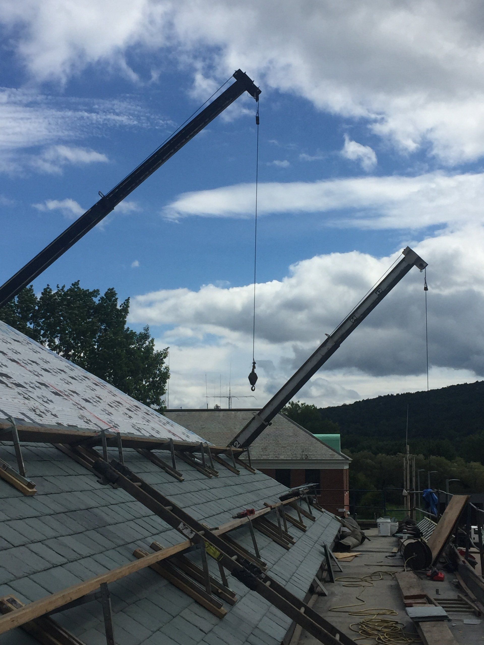 A crane is being used to remove shingles from a roof
