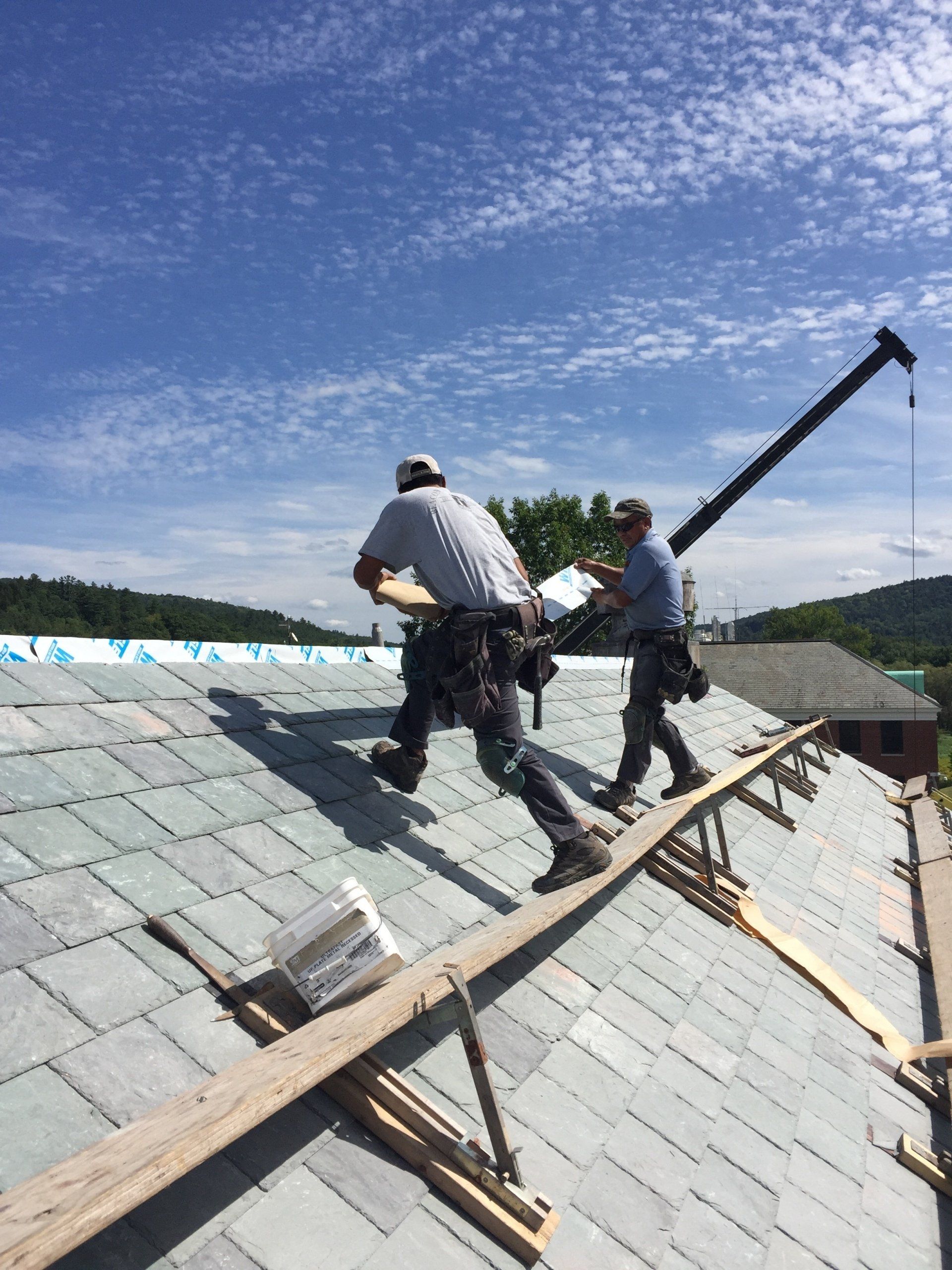 Two men are working on the roof of a house.
