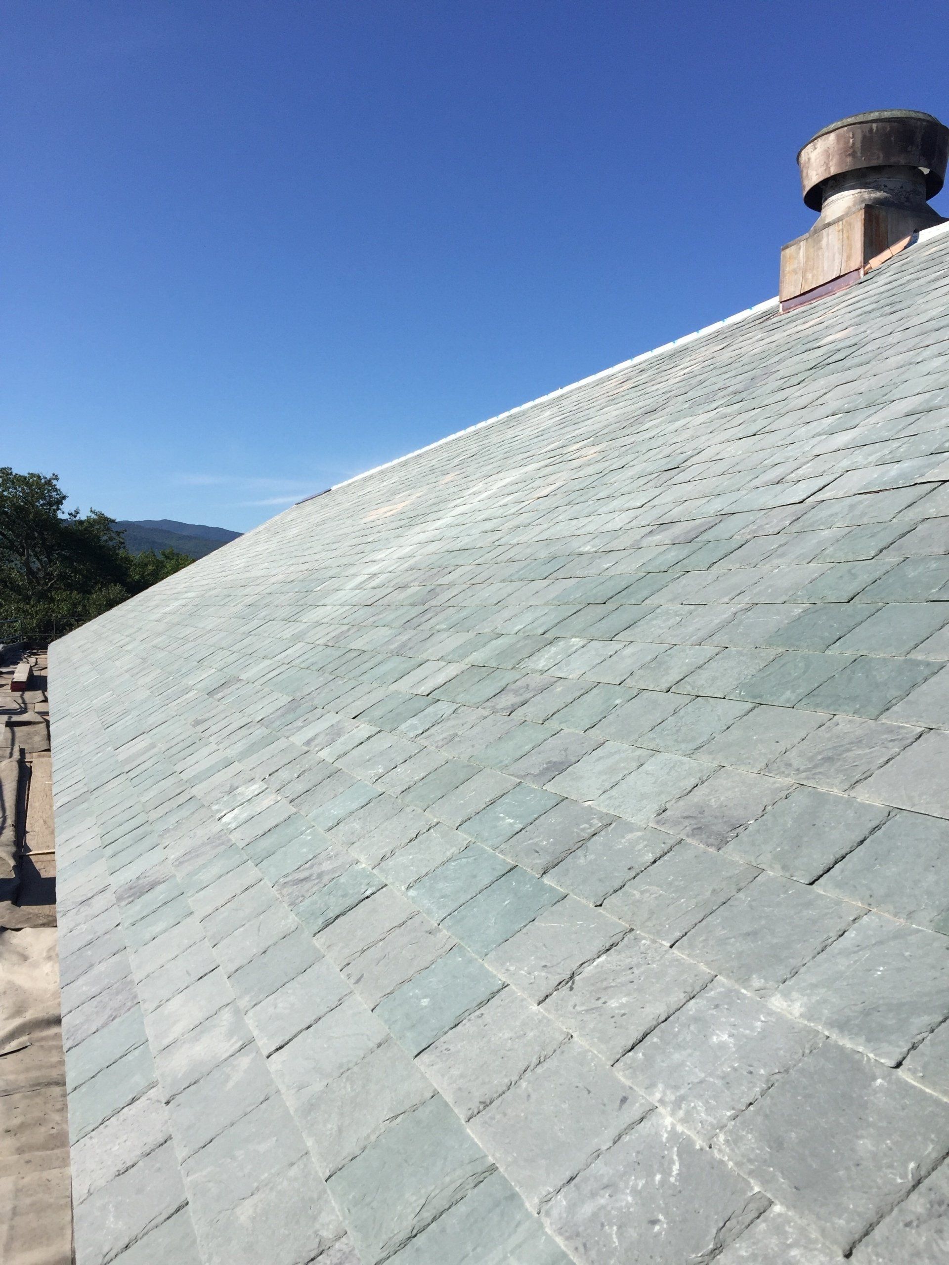 A roof with a chimney on it and a blue sky in the background