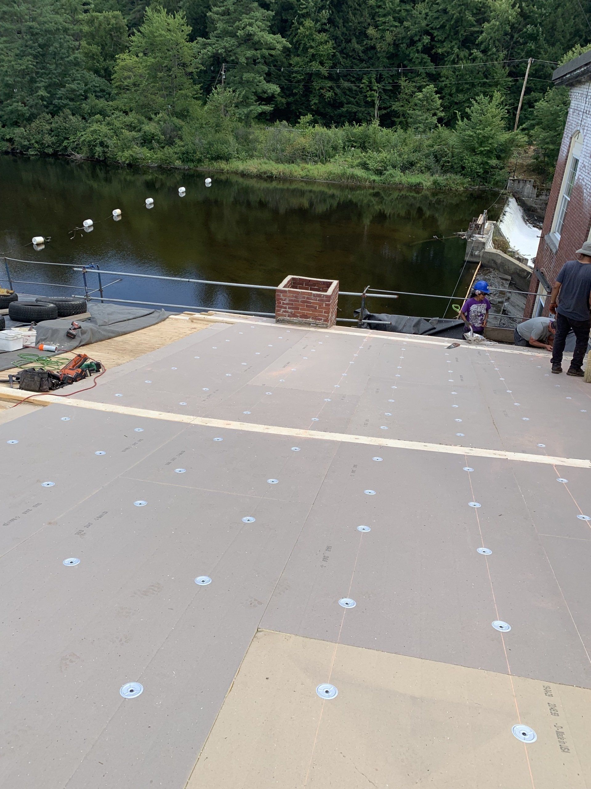 A man is standing on a dock next to a body of water.