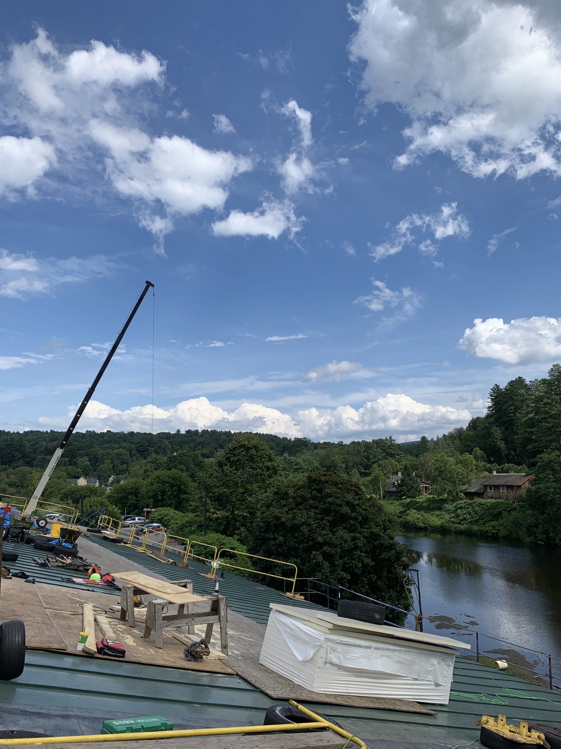 A large crane is sitting on top of a roof next to a body of water.