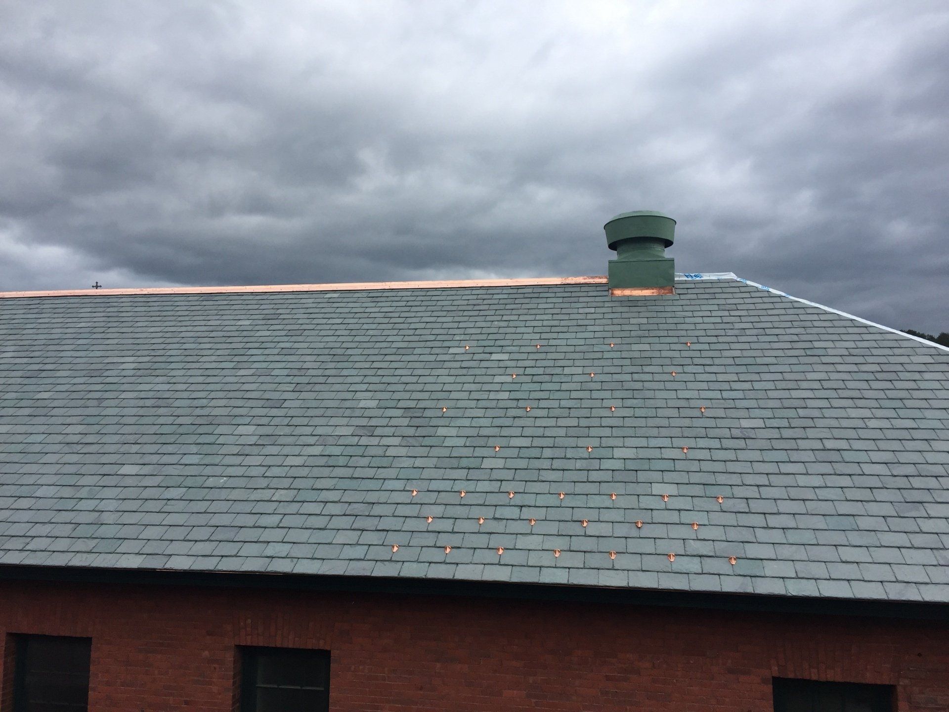 A roof with a chimney on it and a cloudy sky in the background