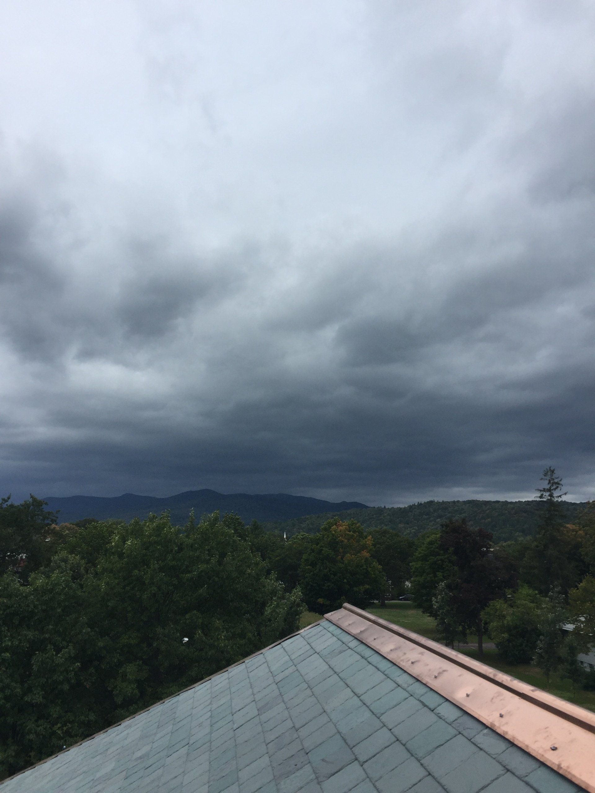 A view of a roof with a cloudy sky in the background.