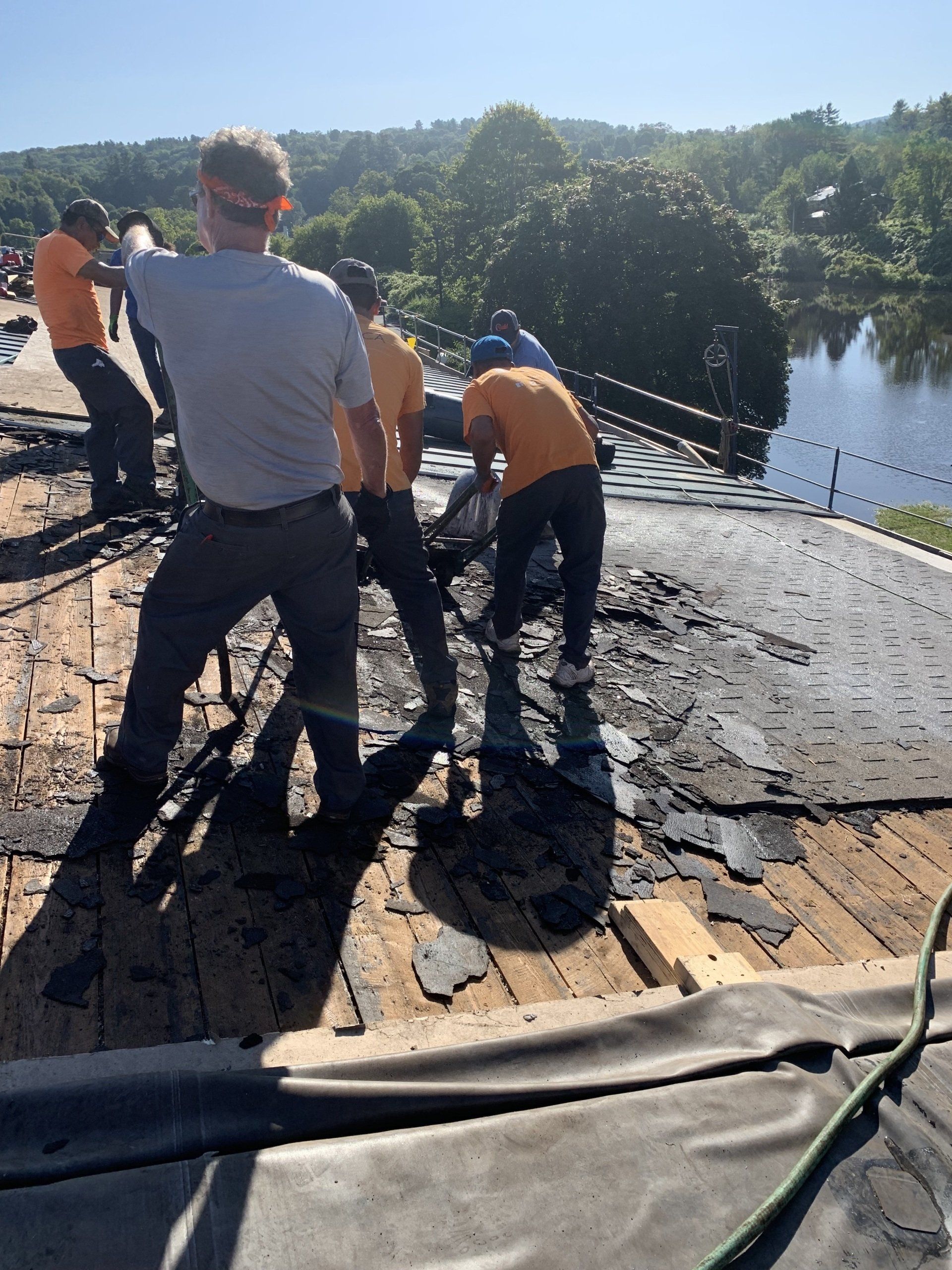 A group of people are working on a roof with a river in the background.
