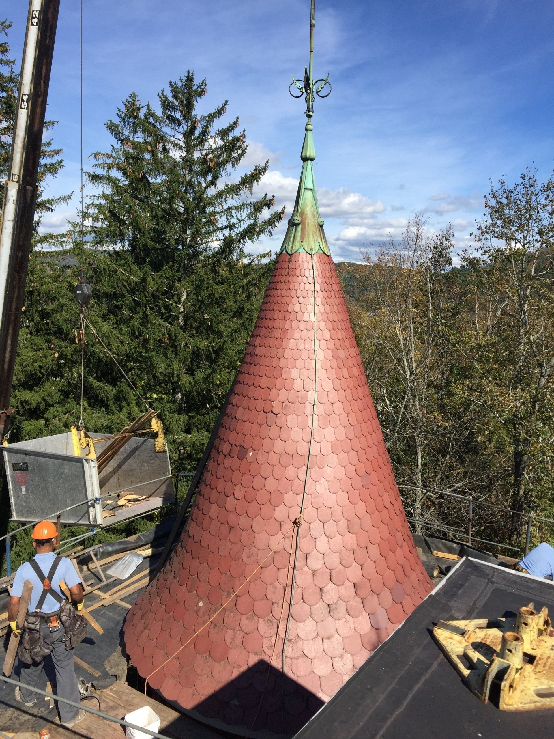 A red cone with a copper top is being built on top of a building.