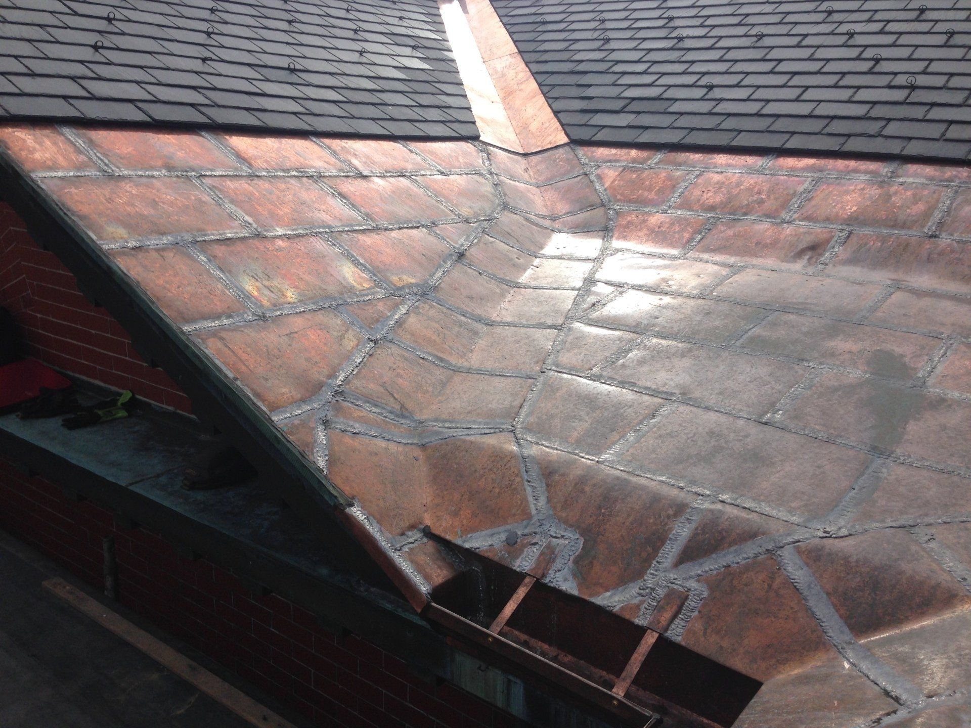 A close up of a copper roof with black shingles