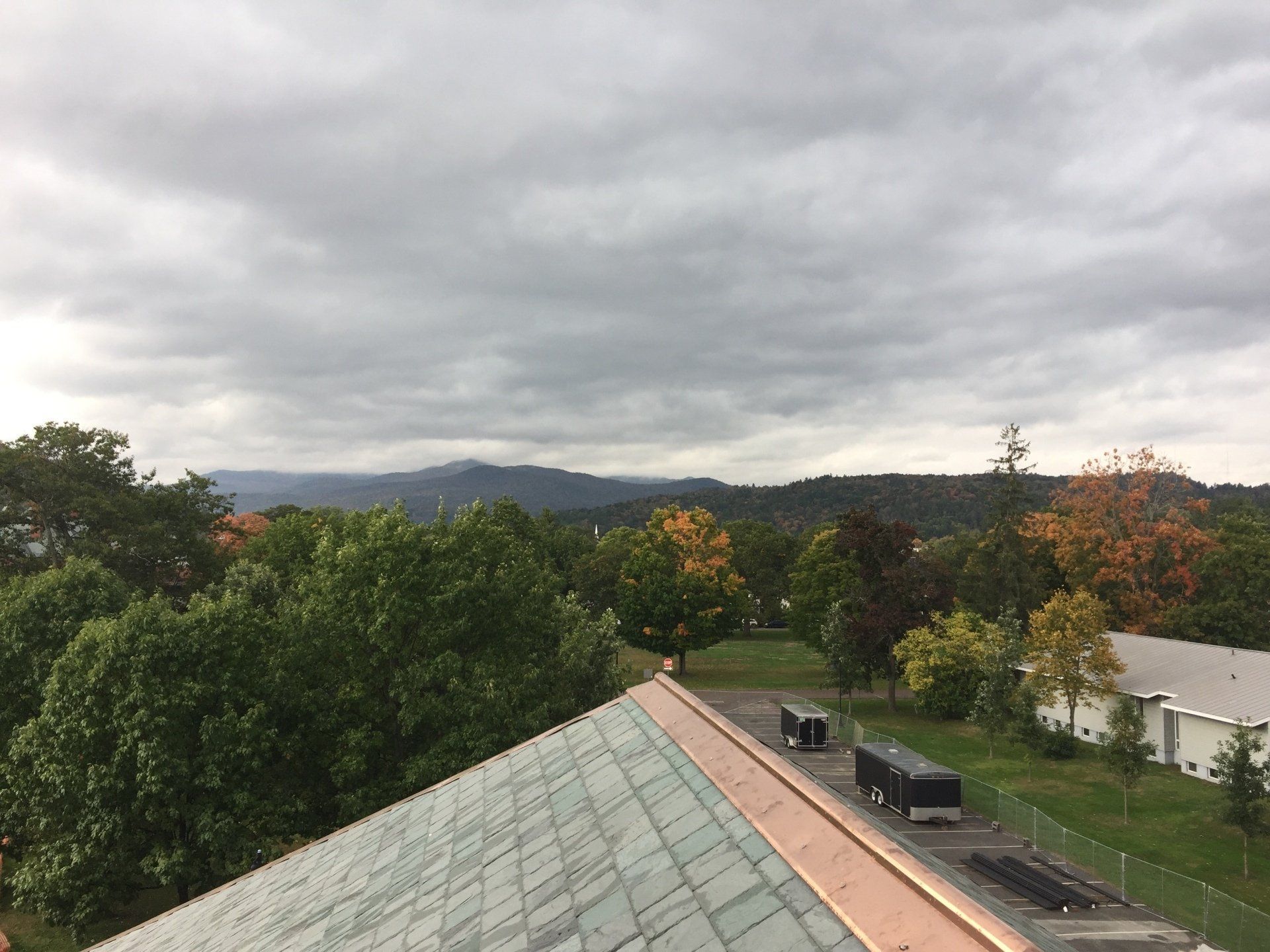 An aerial view of a roof with trees and mountains in the background