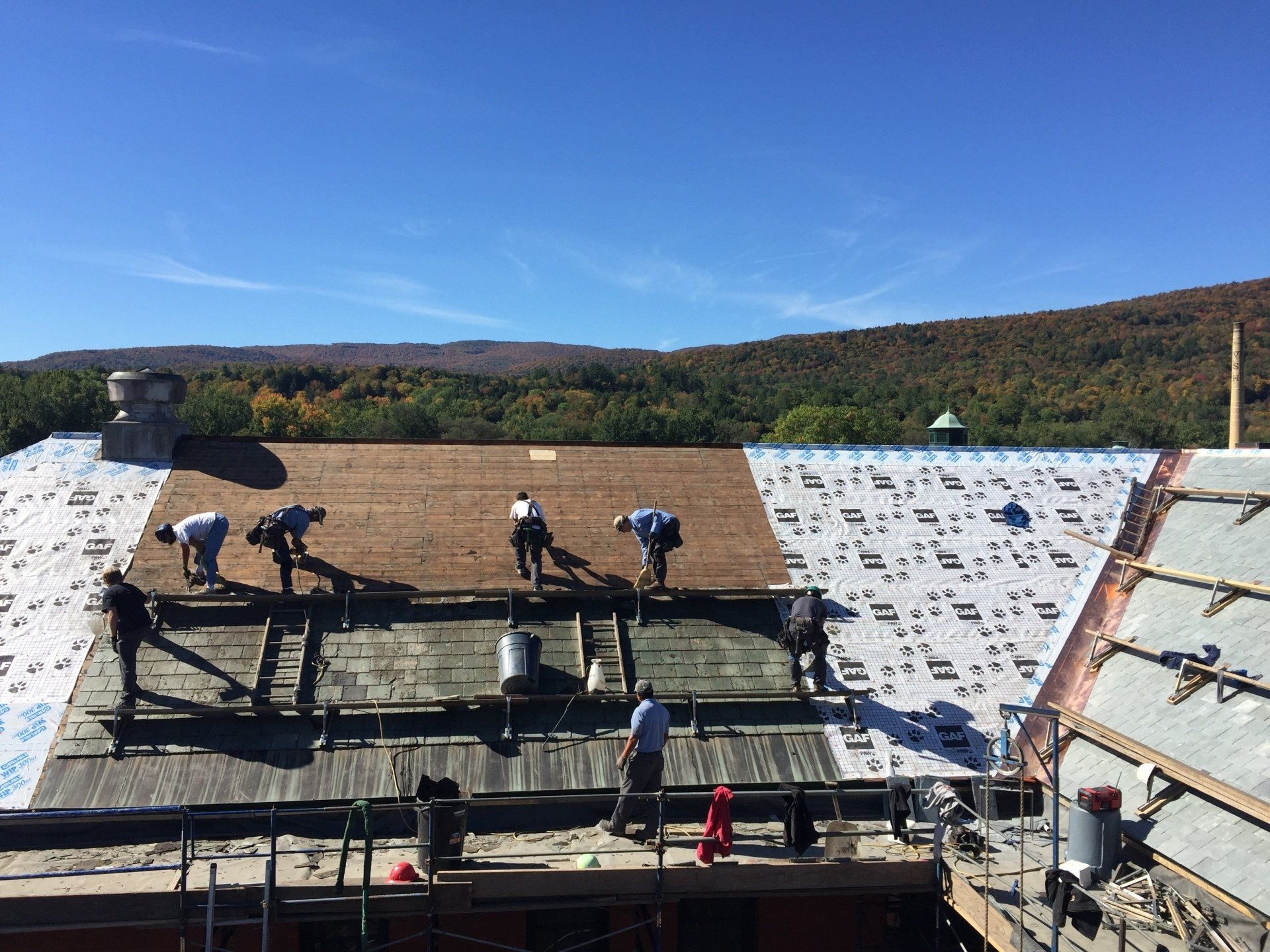 Professional roofers installing a new roof on a large building.