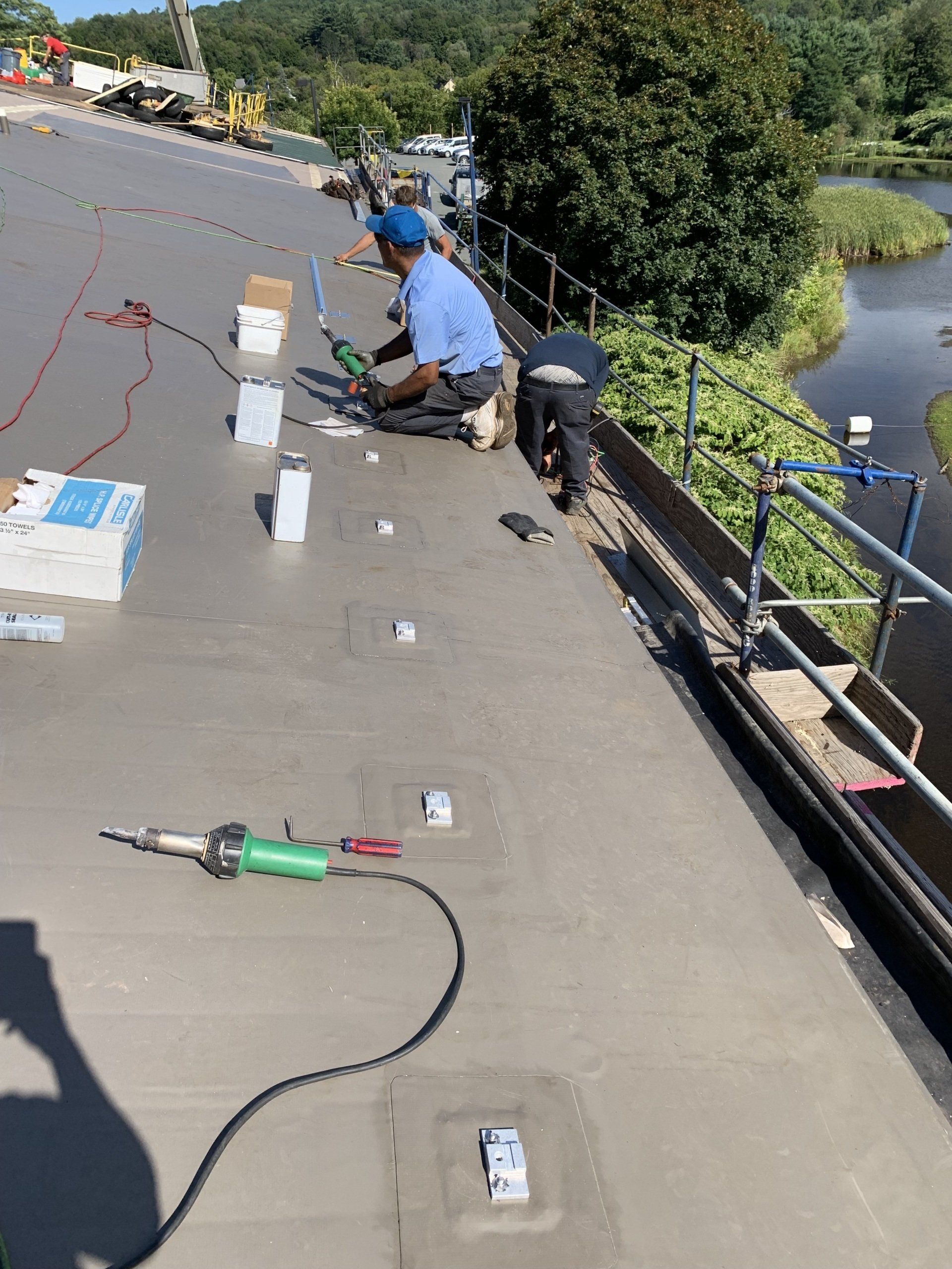 A man is working on a roof next to a river.