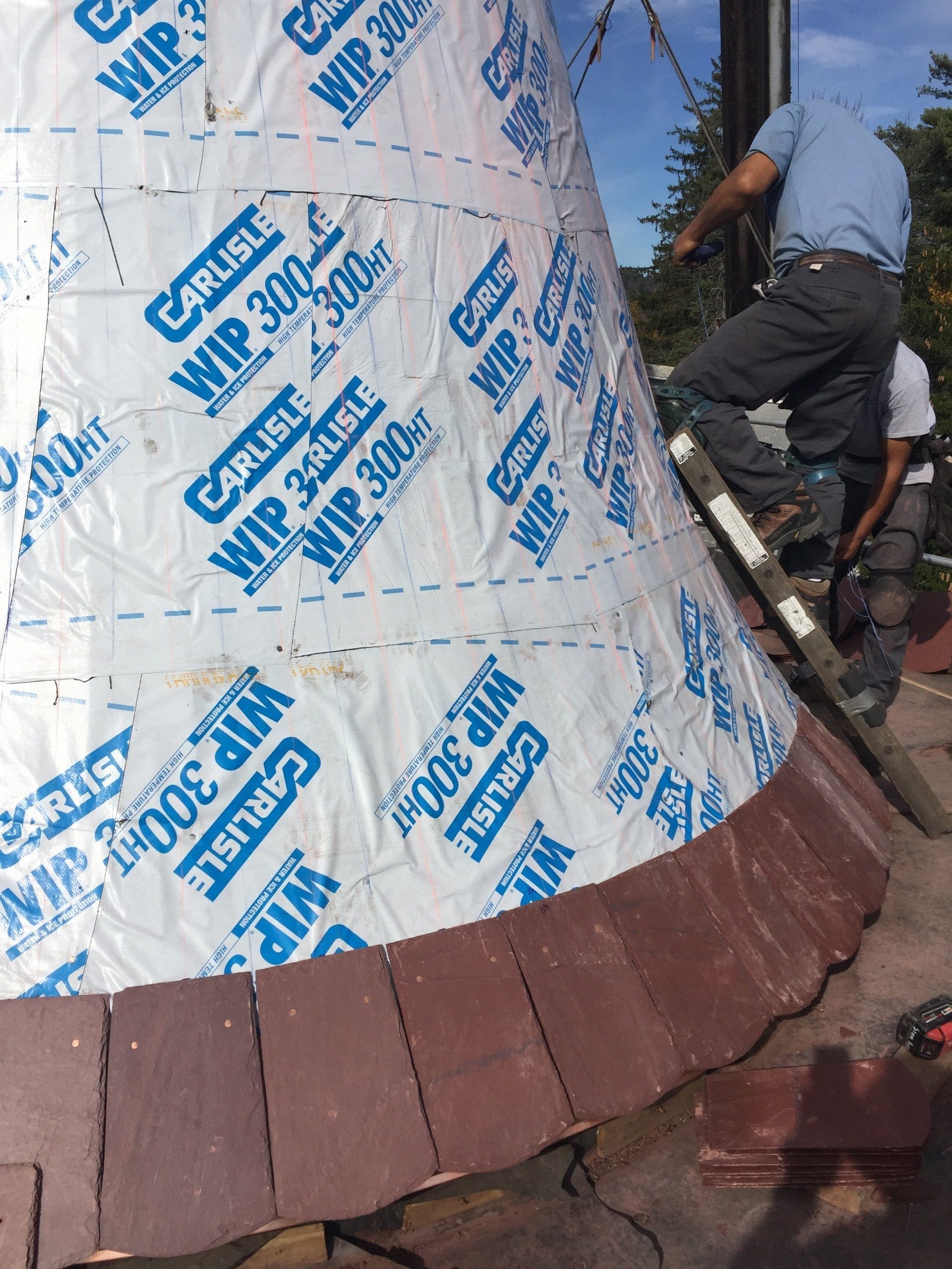A man is standing on a ladder next to a large piece of paper that says carlisle on it