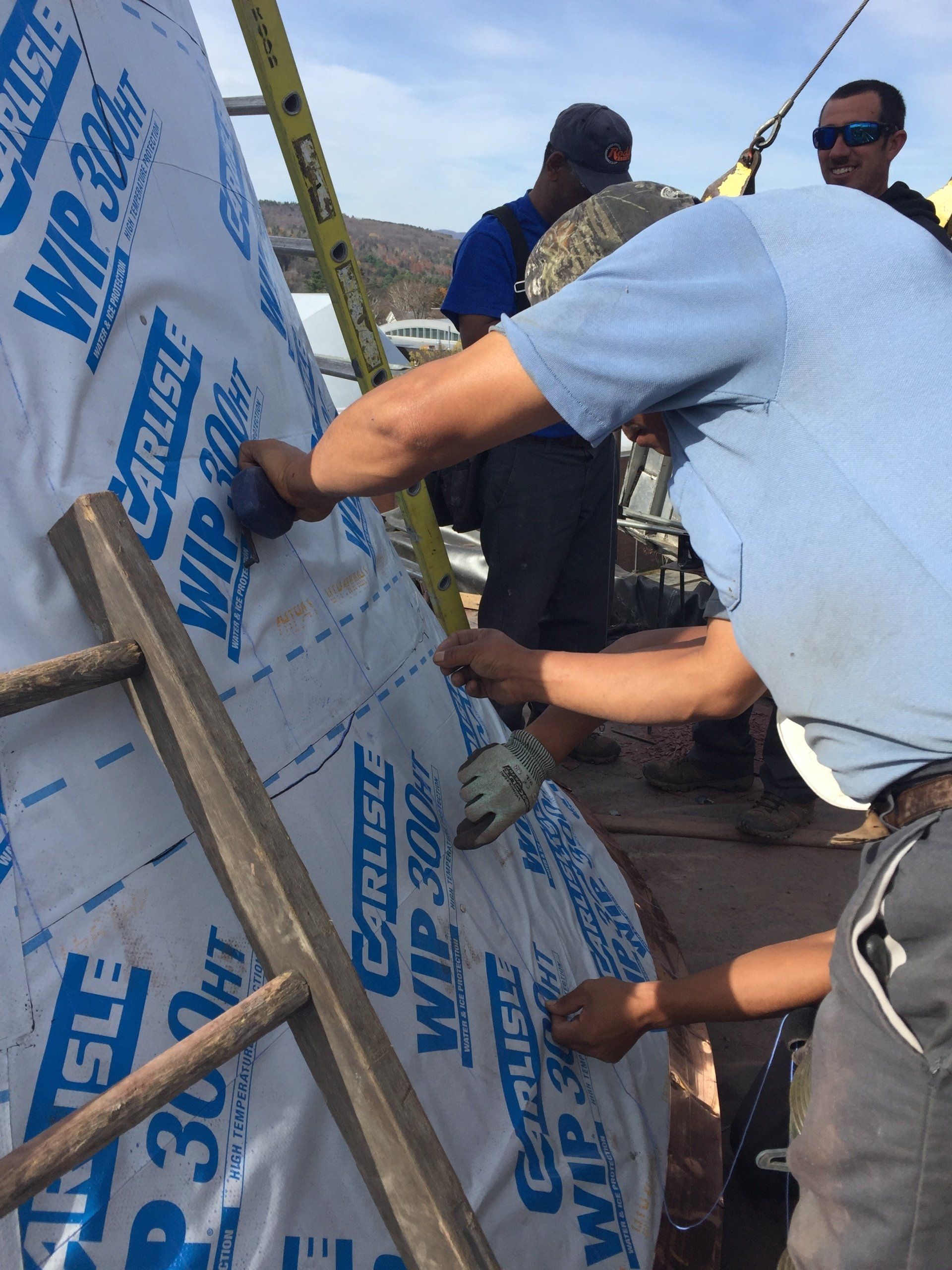 A group of men are working on a building and one of them is wearing sunglasses
