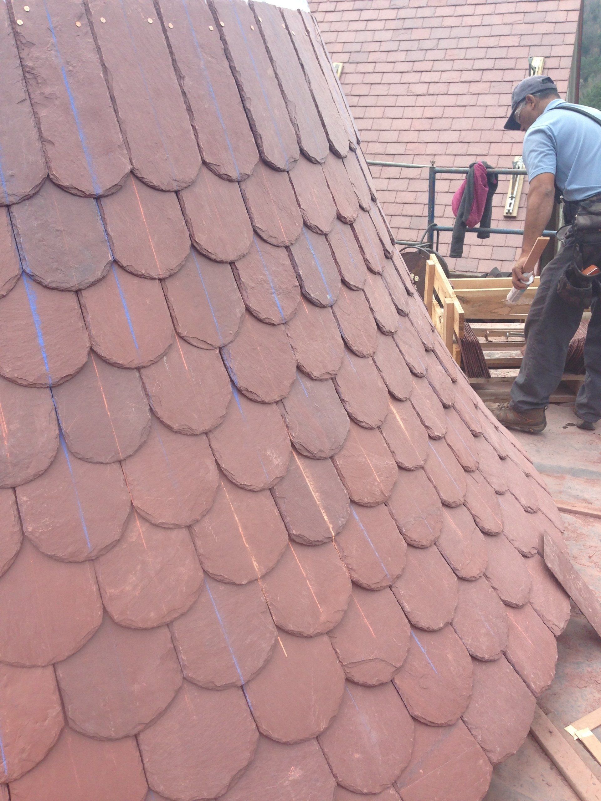 A man standing on top of a roof with red tiles