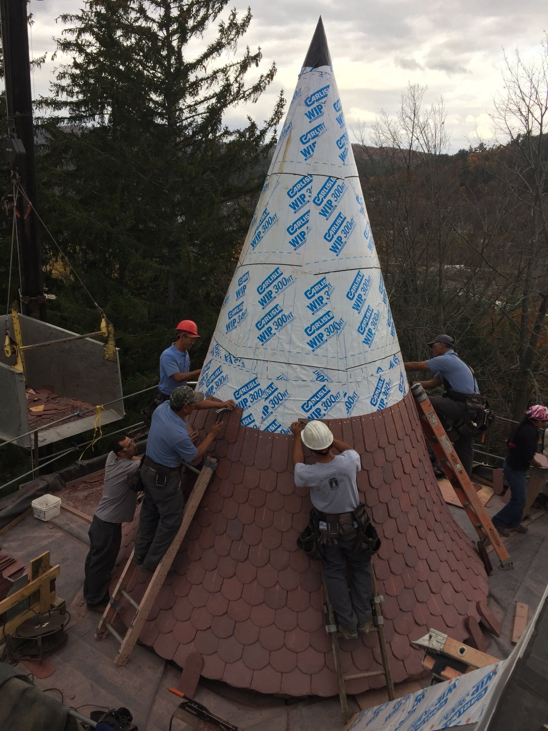 A group of men are working on a large cone on top of a roof.