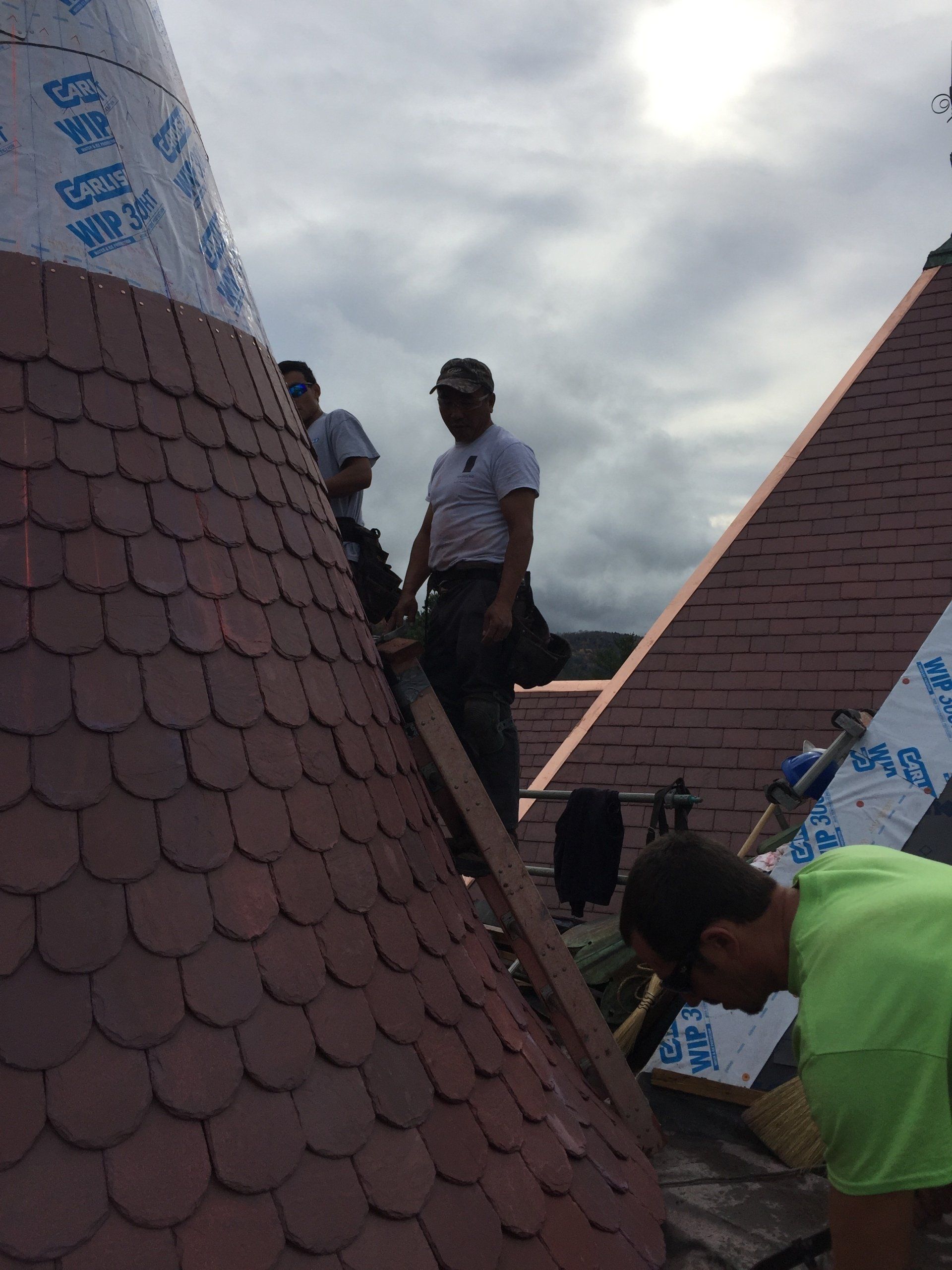 A man in a green shirt is working on a roof.