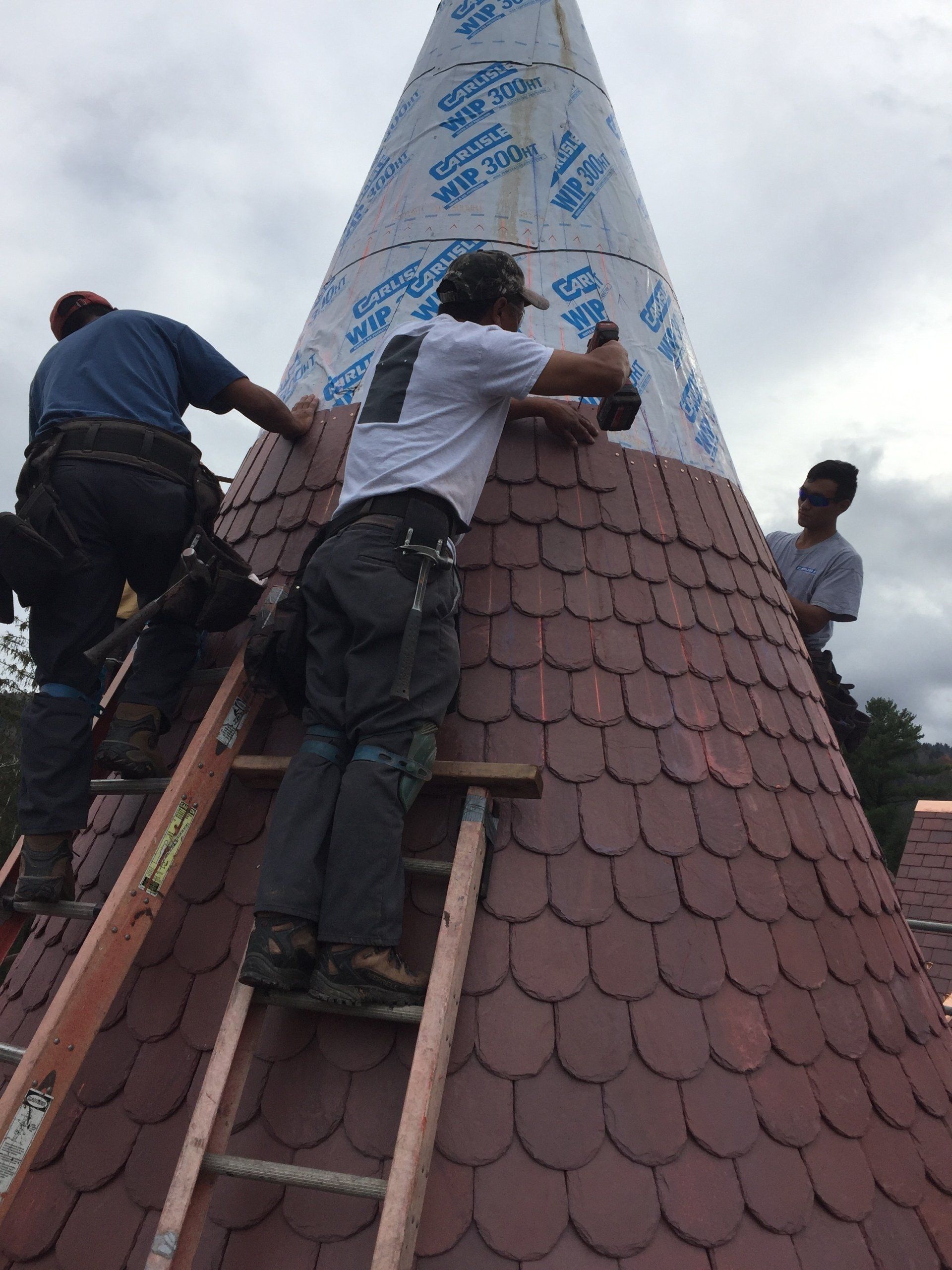 A group of men are working on a cone shaped roof