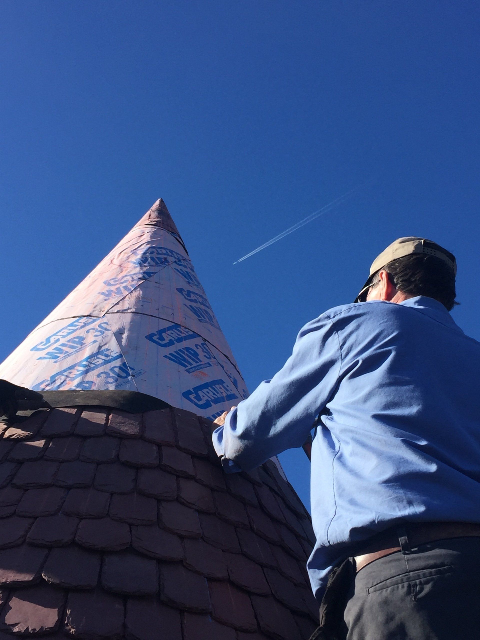 A man in a blue shirt is working on a roof