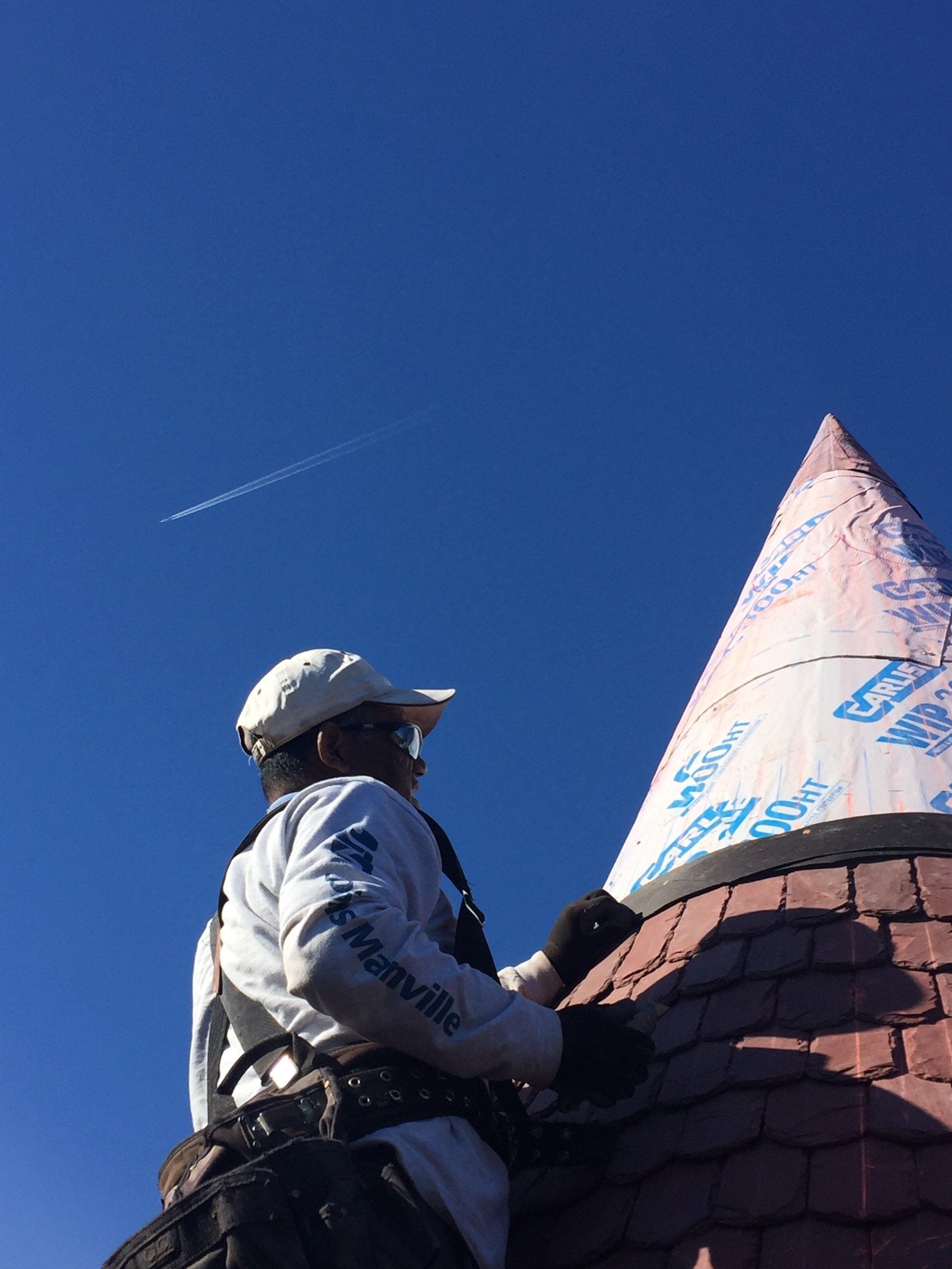 A man is working on a roof with a cone on top of it