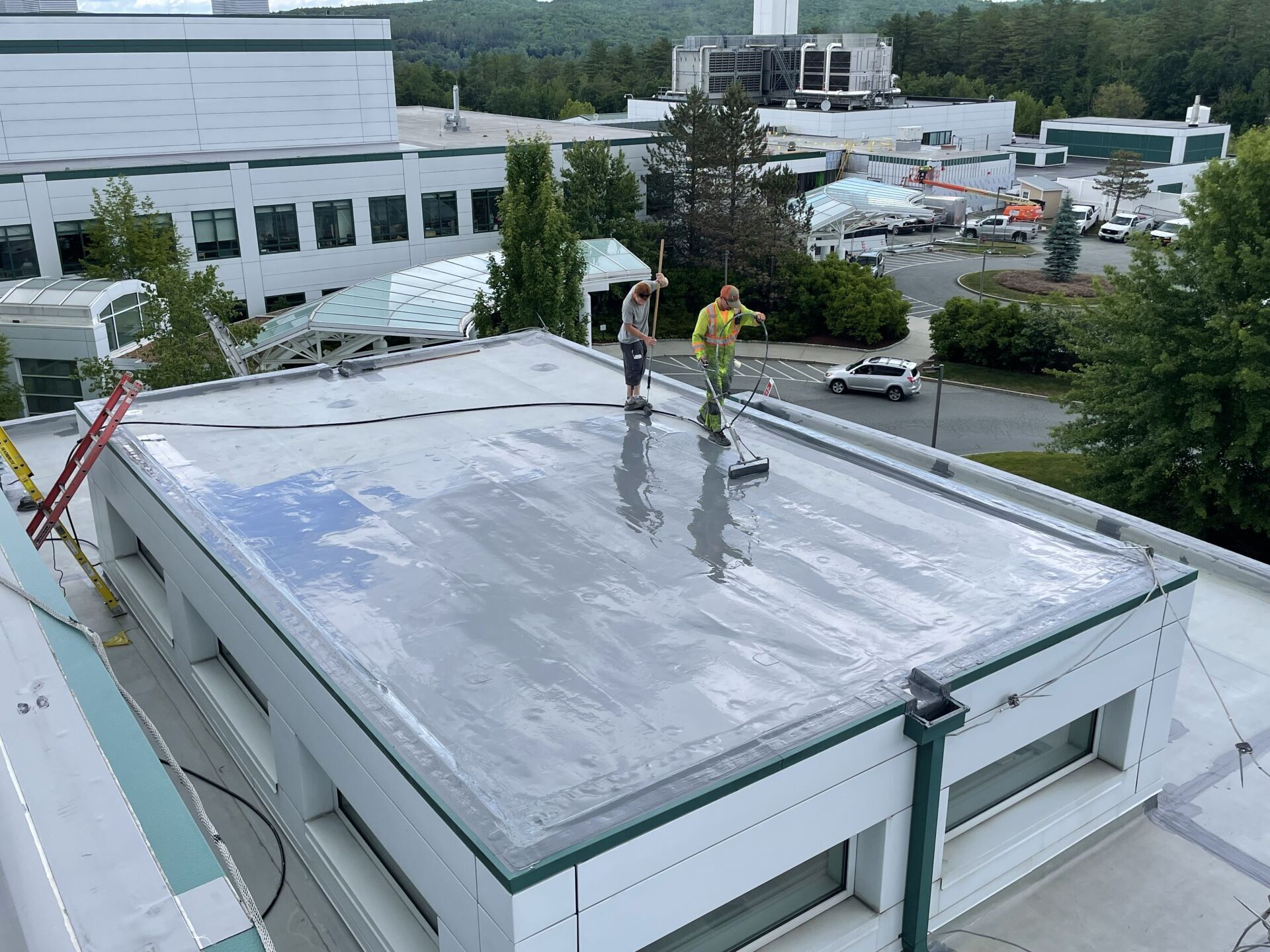 Two men are working on a commercial flat roof of a building in Vermont