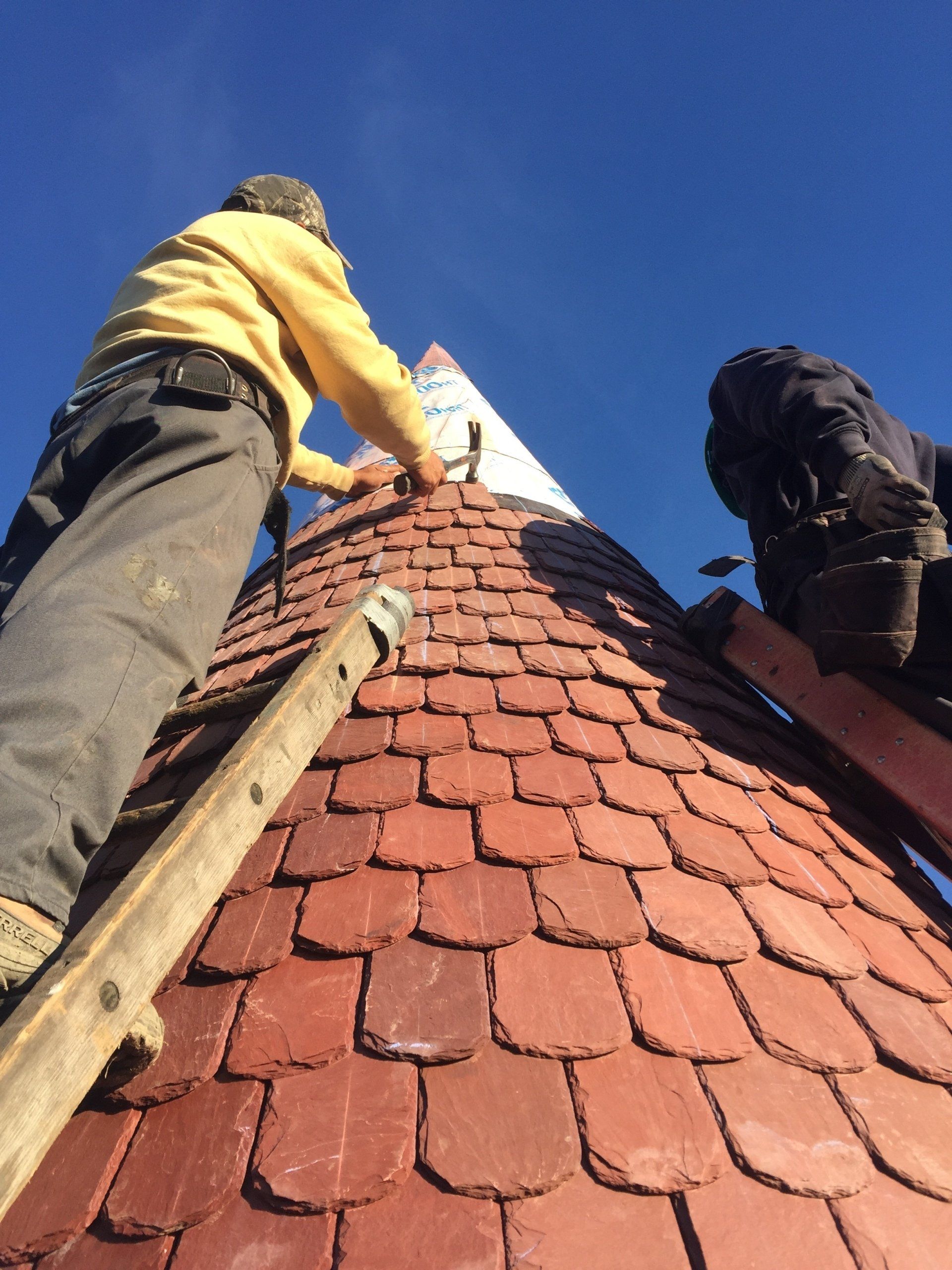 Two men are working on the roof of a building