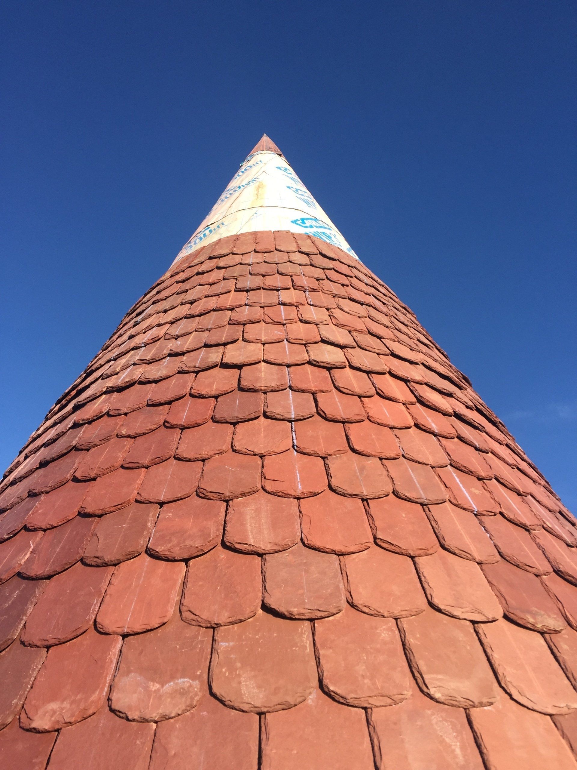 Looking up at a pyramid shaped roof with a blue sky in the background