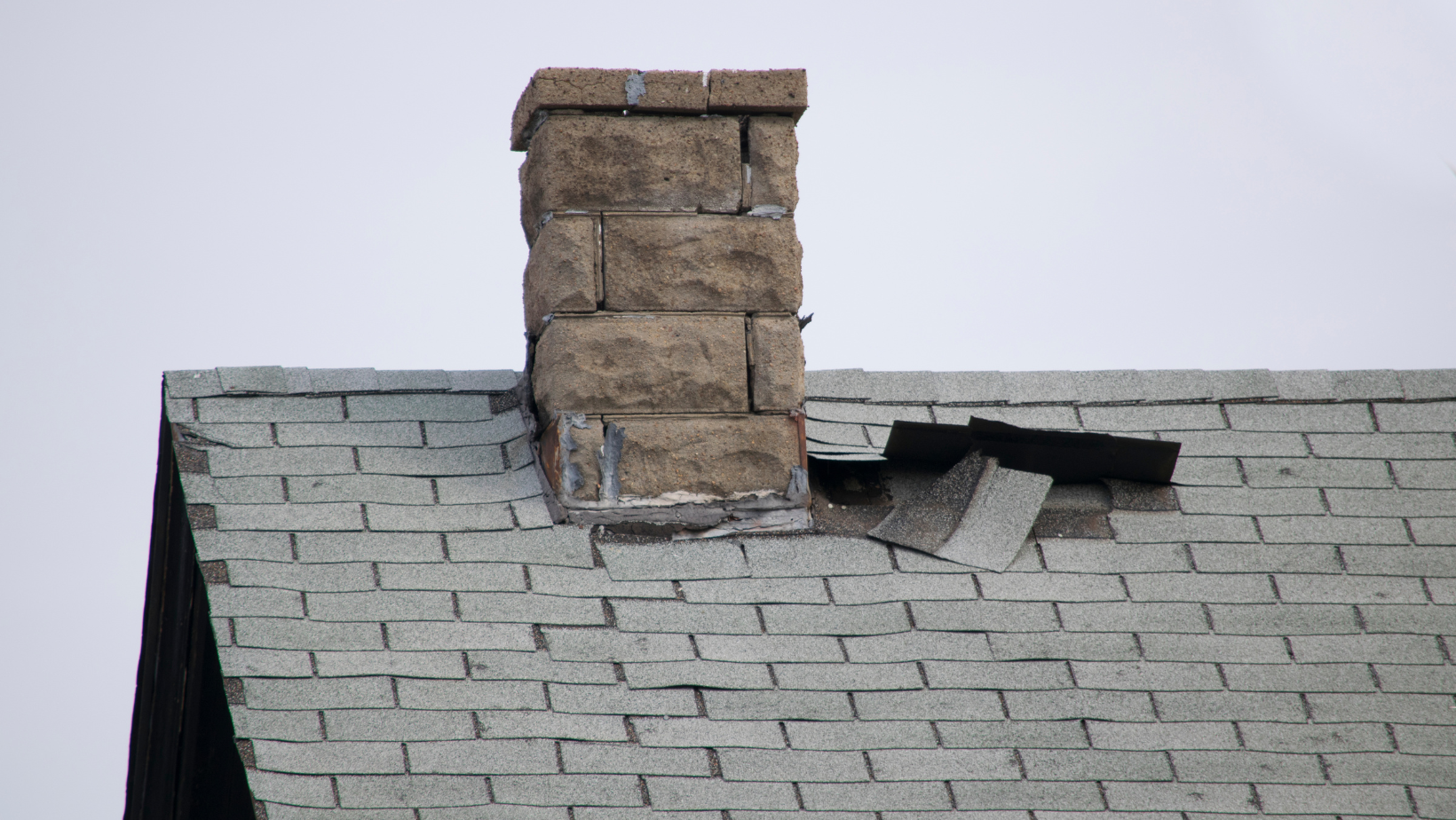 An asphalt shingle roof suffers damage near the chimney in Vermont.