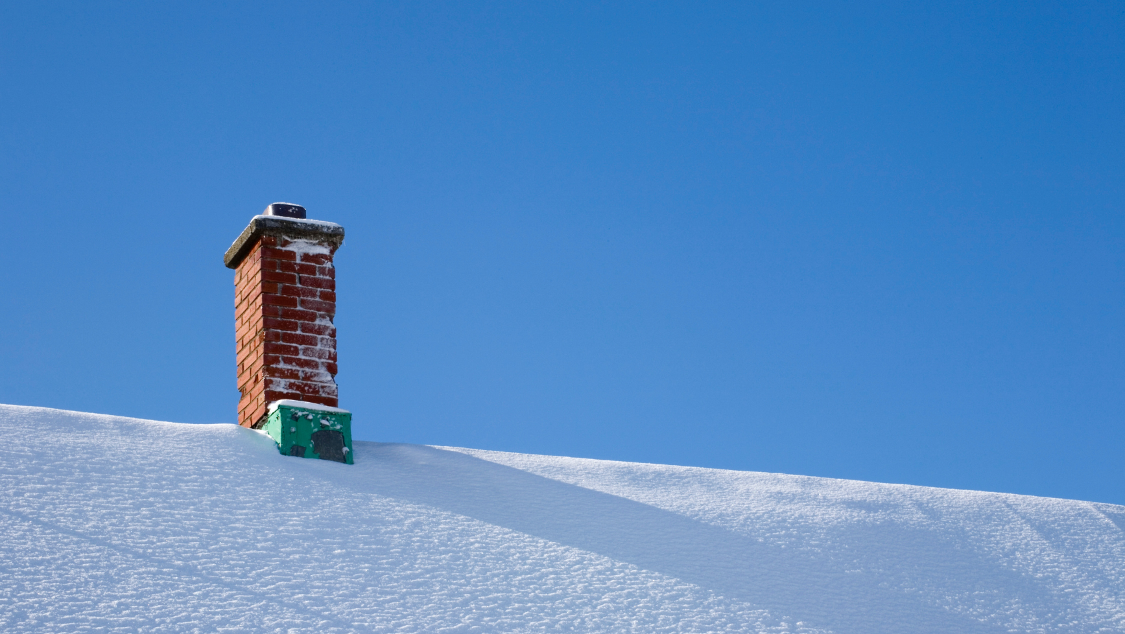 Snow-covered roof with brick chimney in Vermont