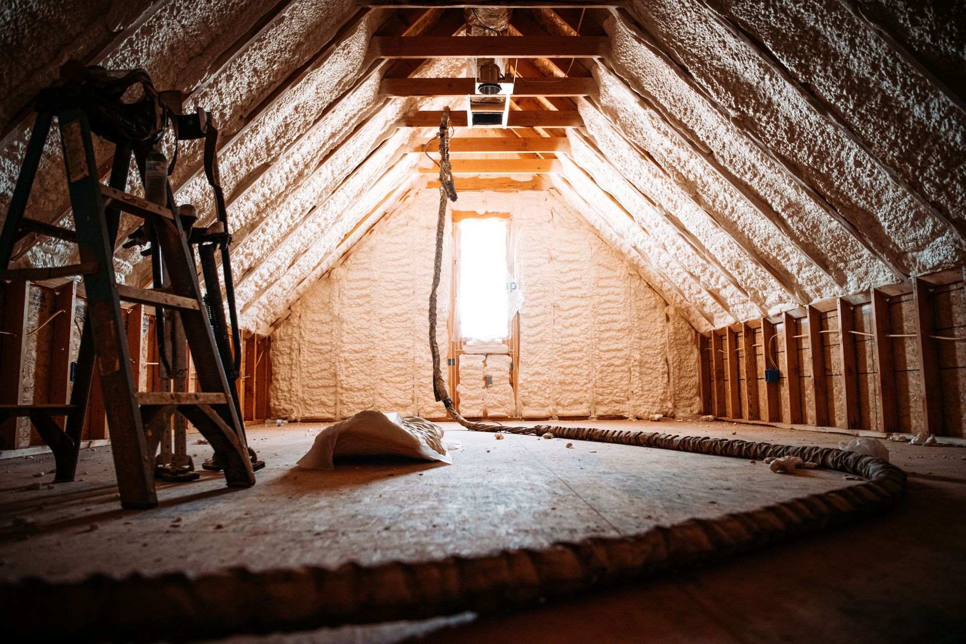 A ladder is sitting in the attic of a house with minimal ventilation