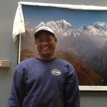 A man is standing in front of a picture of mountains.